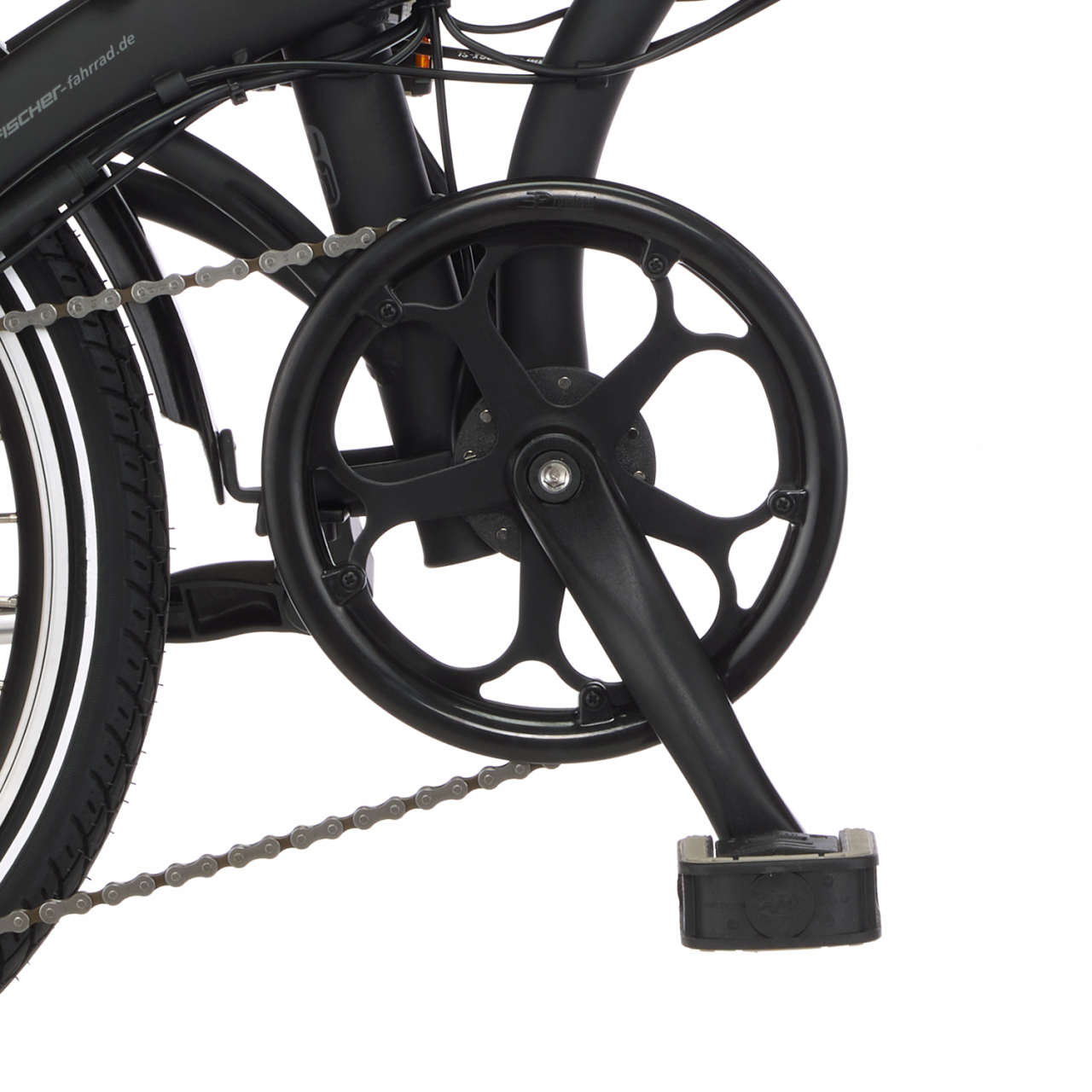 Zbliżenie czarnego mechanizmu korbowego roweru, łańcucha i koła. Mechanizm korbowy ma okrągły kształt. Widoczna opona z białymi paskami.