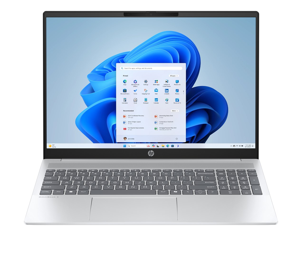 Srebrny laptop HP jest otwarty, wyświetlając pulpit Windows 11. Ekran pokazuje niebieski wir i ikony aplikacji. Klawiatura widoczna.