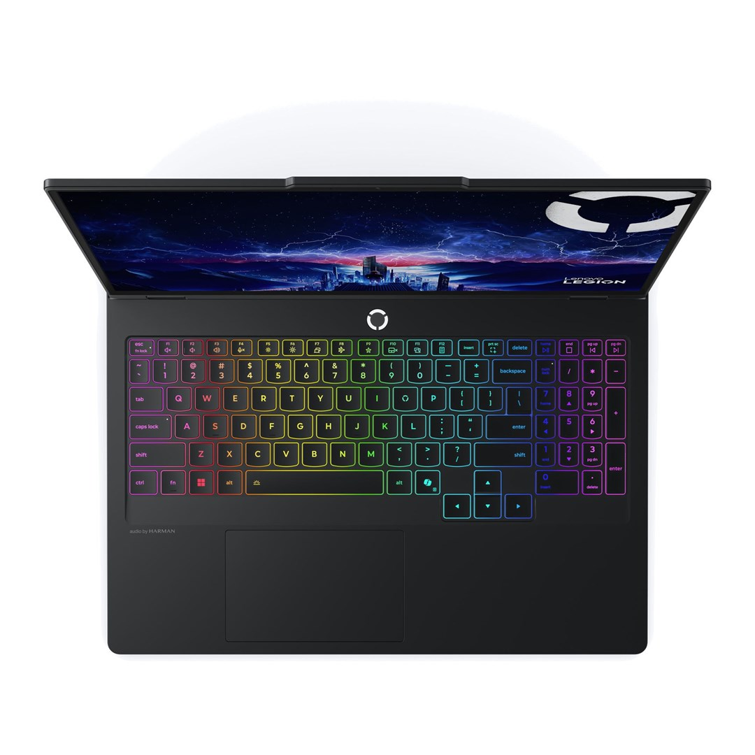 Czarny laptop z kolorową klawiaturą, otwarty na stole. Ekran wyświetla nocne miasto i logo Legion.
