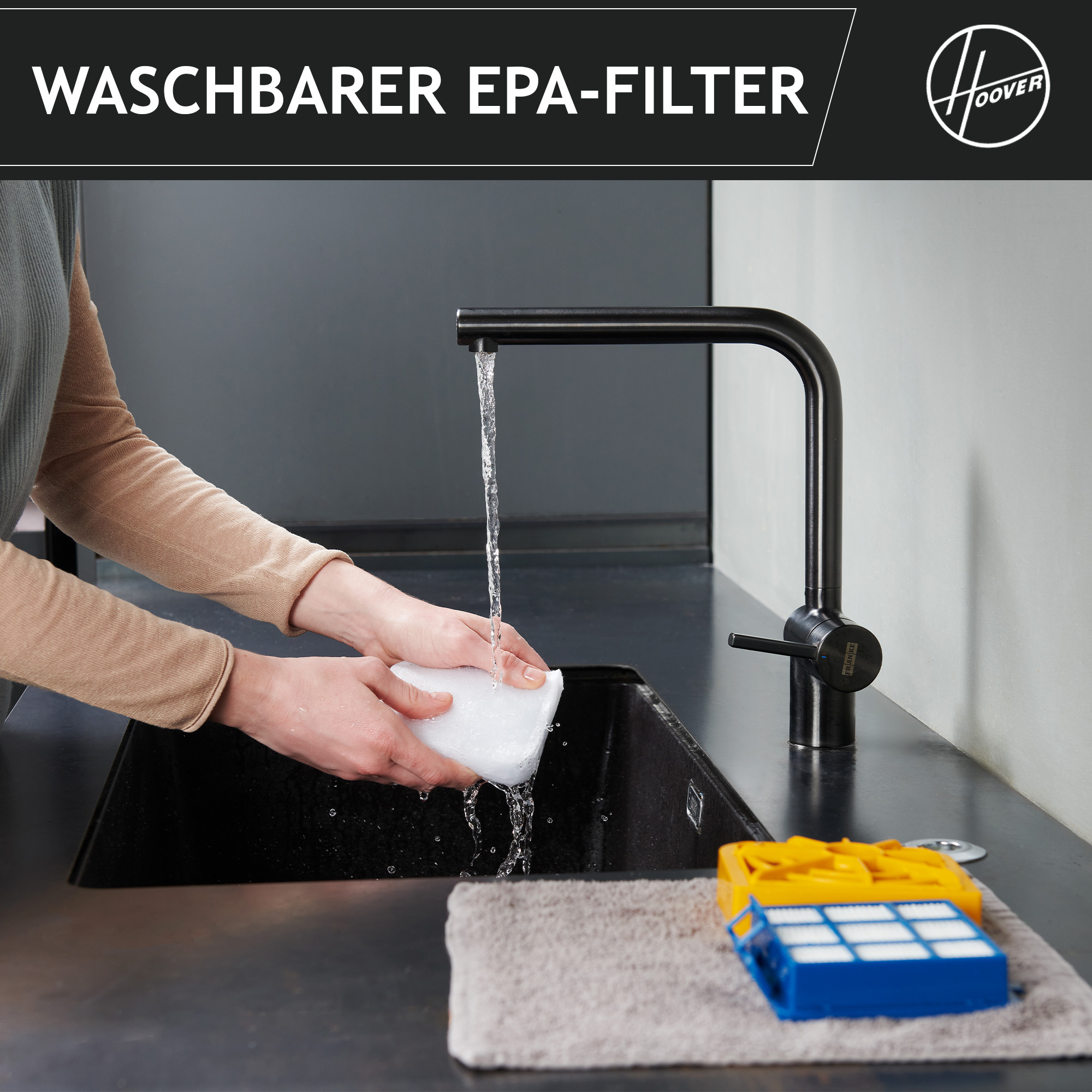 Osoba myje biały filtr pod czarnym kranem. Żółty i niebieski filtr leży na ręczniku. Widoczne logo Hoover.