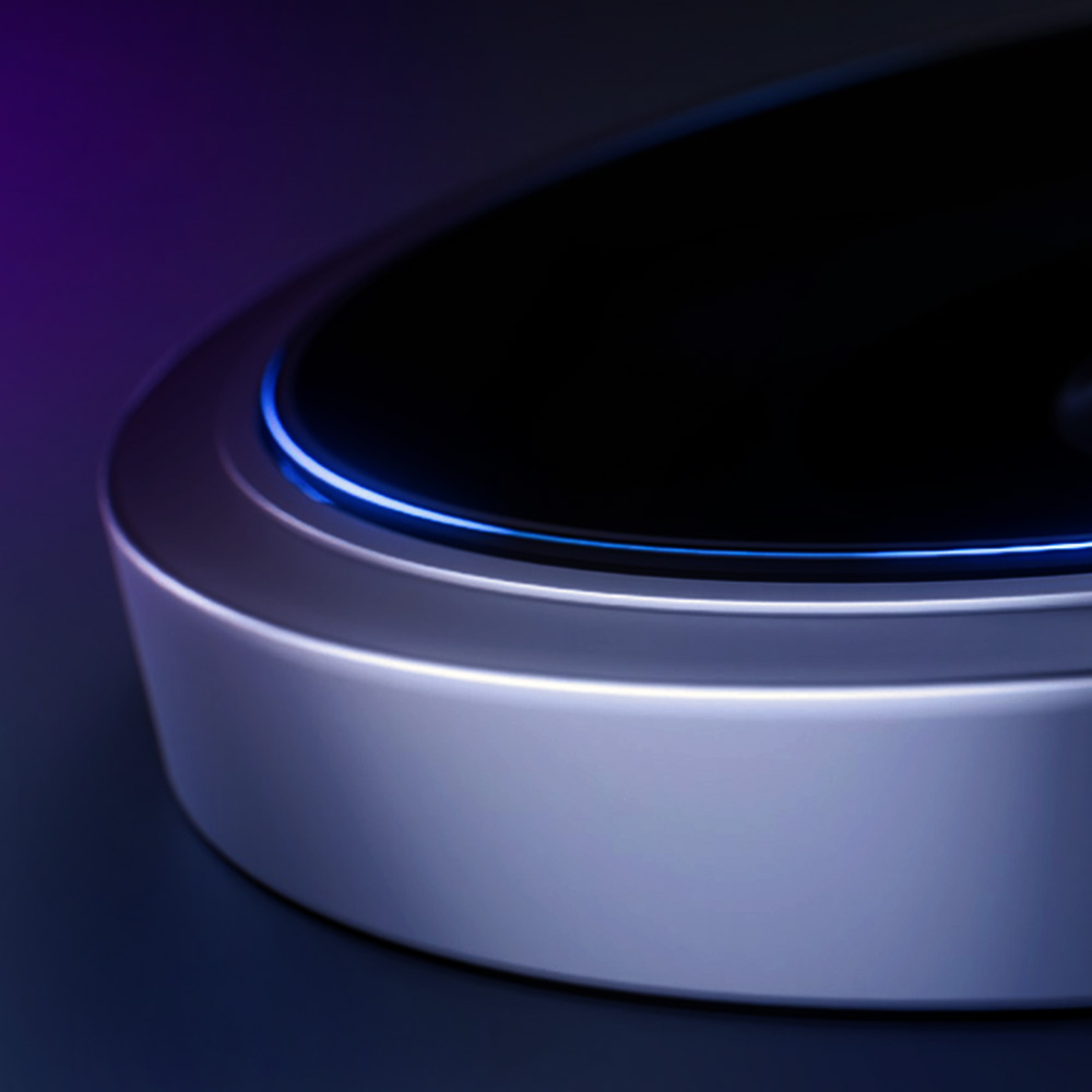 Zbliżenie srebrnego urządzenia z czarnym blatem. Ma niebieskie światło wokół krawędzi. Tło jest ciemne i stopniowane.