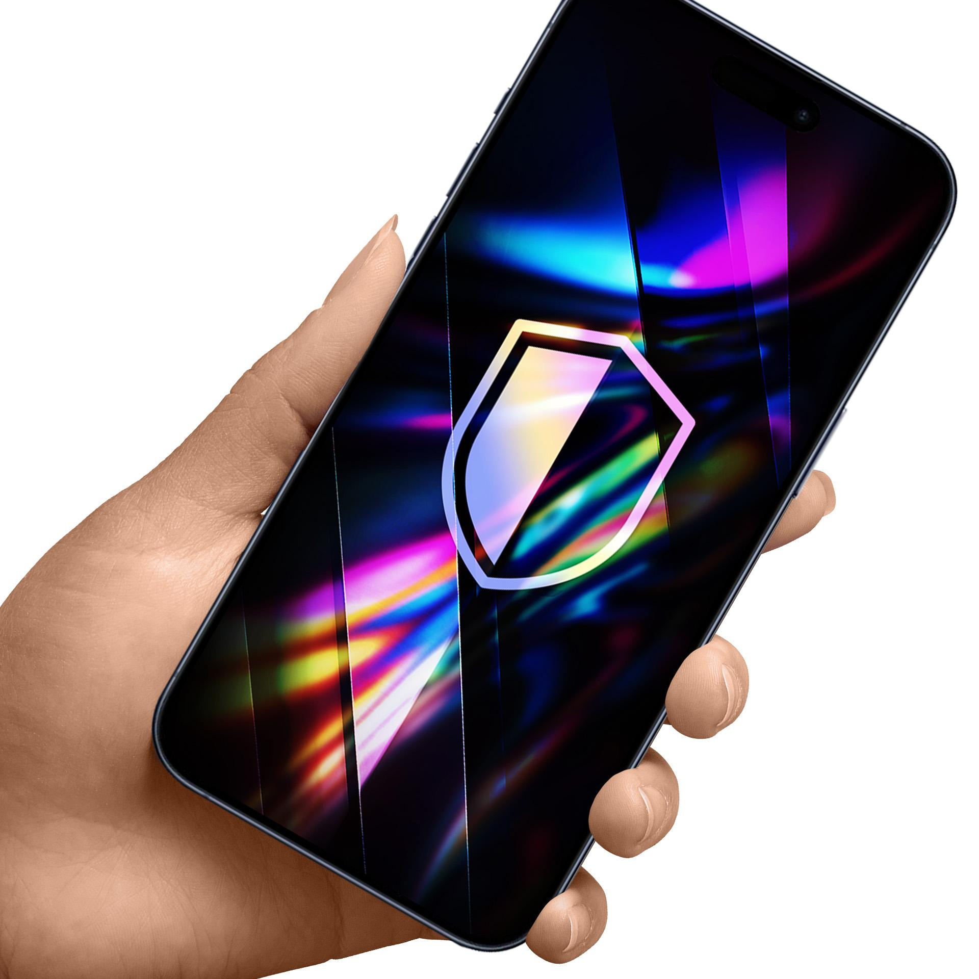 Dłoń trzyma smartfon z ikoną tarczy na ekranie. Telefon wyświetla kolorowe, abstrakcyjne tło.
