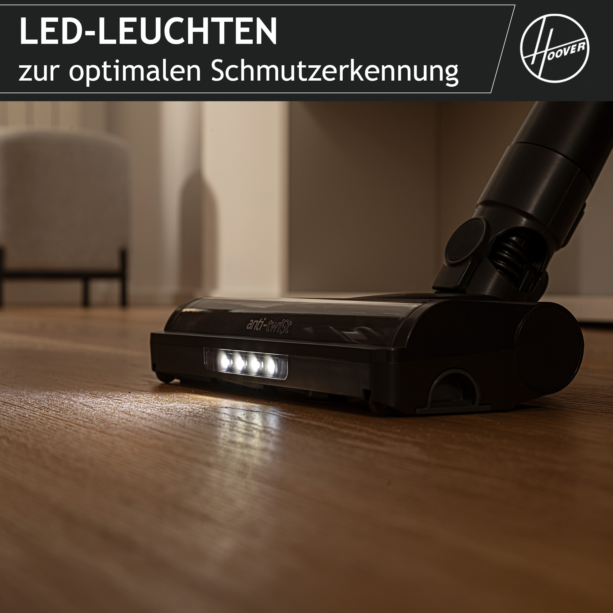Nahaufnahme eines schwarzen Staubsaugerkopfes mit LED-Leuchten auf einem Holzboden.