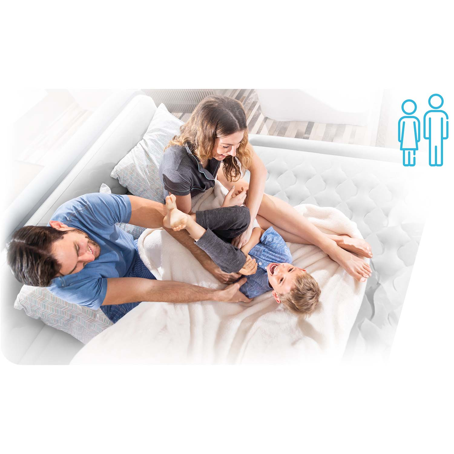 Trzyosobowa rodzina bawi się na białym dmuchanym łóżku. Mężczyzna i kobieta wchodzą w interakcję z śmiejącym się dzieckiem.