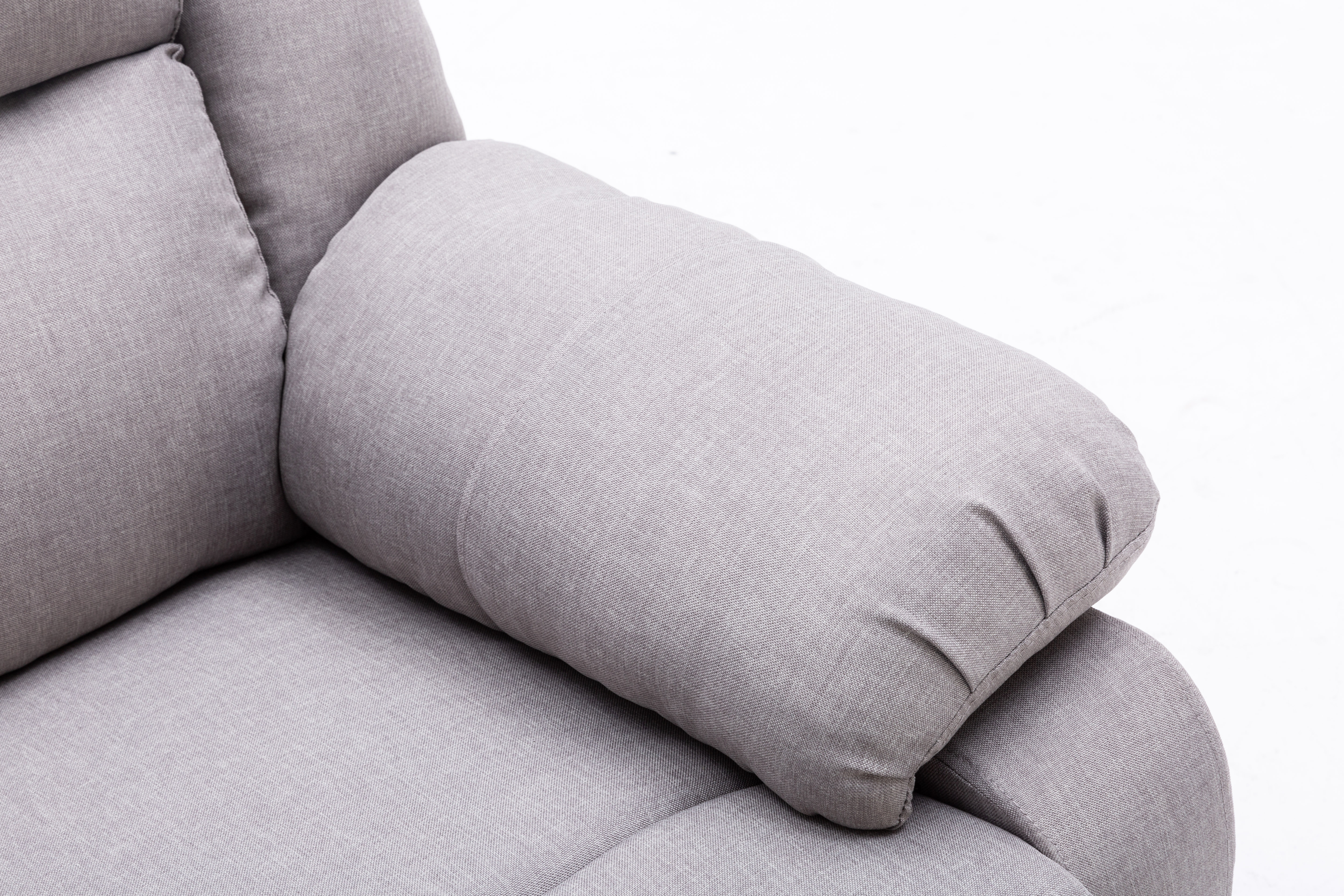 Primer plano de un brazo de sofá gris con una almohada. La tela es texturizada, y el fondo es blanco.