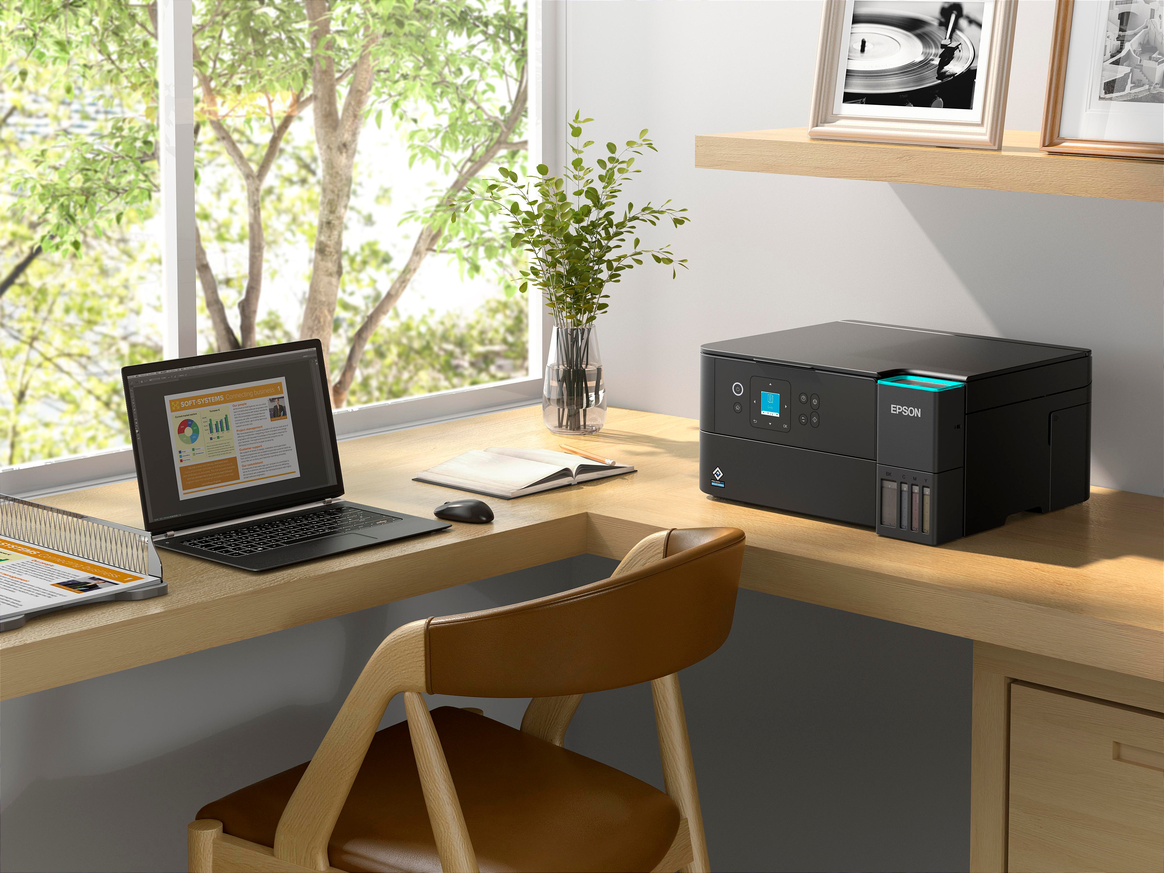 Scena biurowa z laptopem, drukarką i krzesłem w pobliżu okna. Na półce znajdują się oprawione zdjęcia.