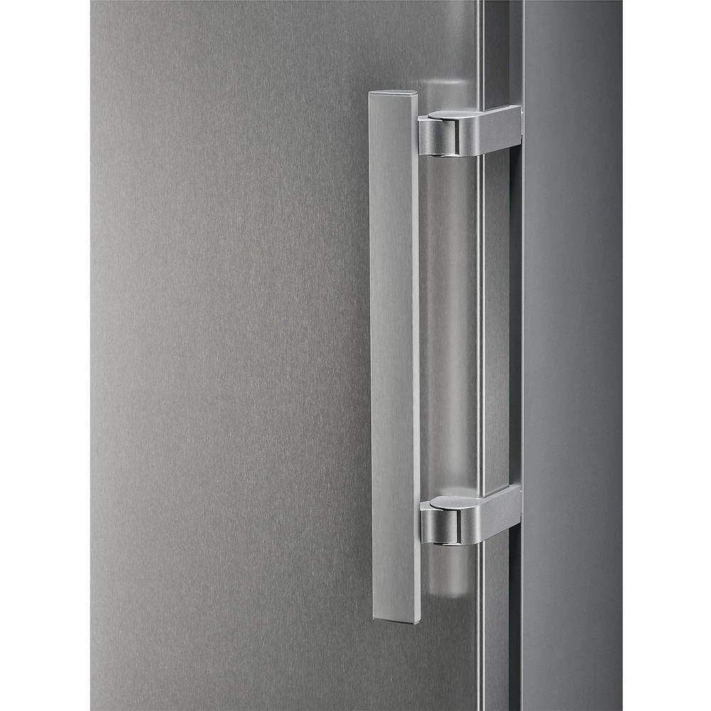 Primer plano de una puerta de nevera de acero inoxidable con un tirador plateado. La puerta es de acero cepillado, y el tirador es vertical.