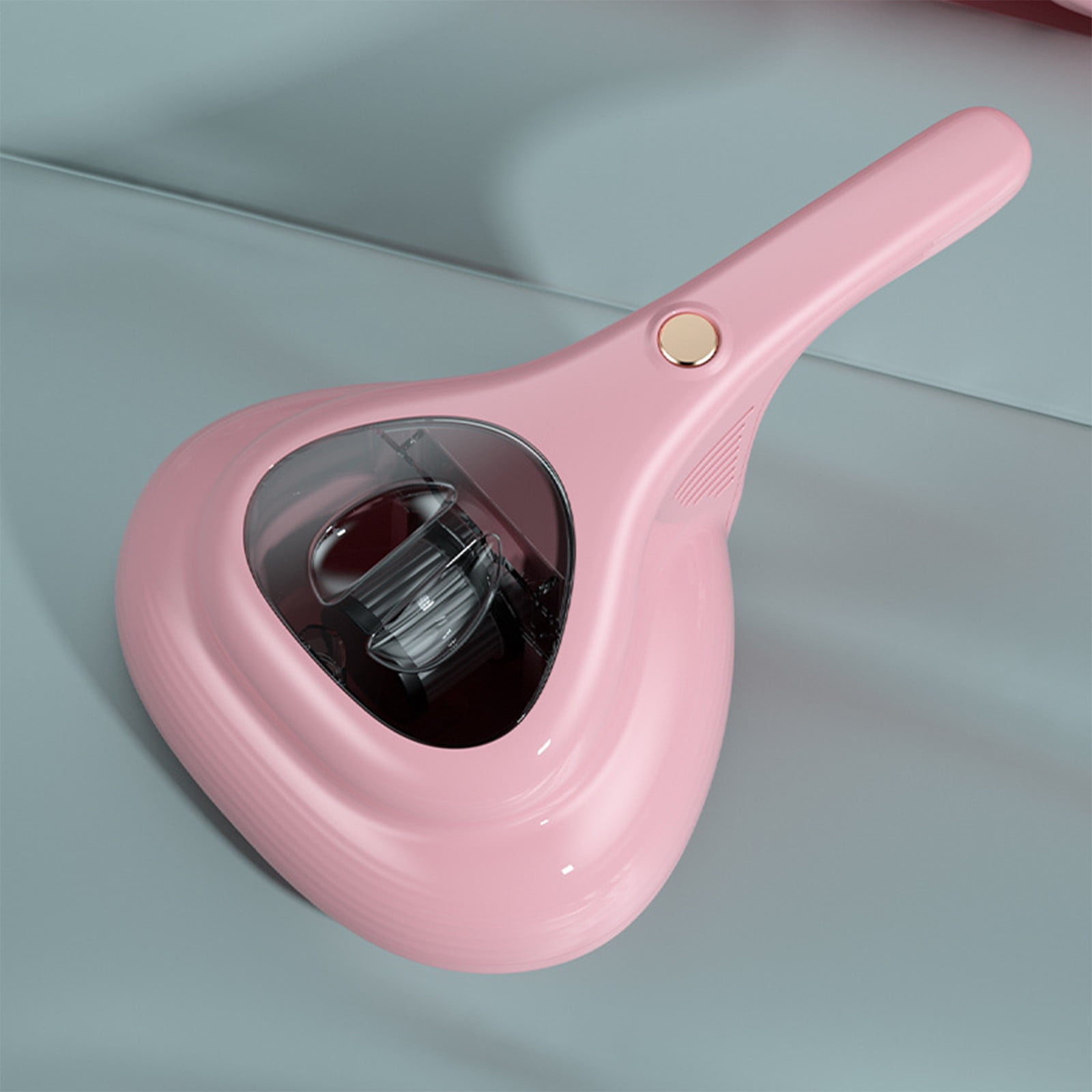Rosa Handstaubsauger mit Knopf und transparentem Staubbehälter auf grauem Untergrund.