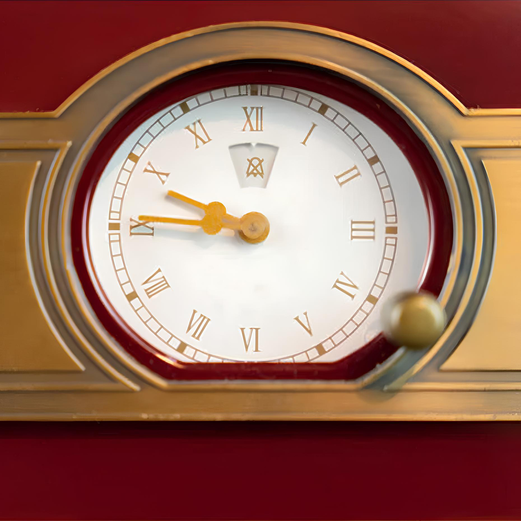 Eine Uhr mit römischen Ziffern auf weißem Zifferblatt, goldenen Zeigern und einem gold-roten Rahmen.