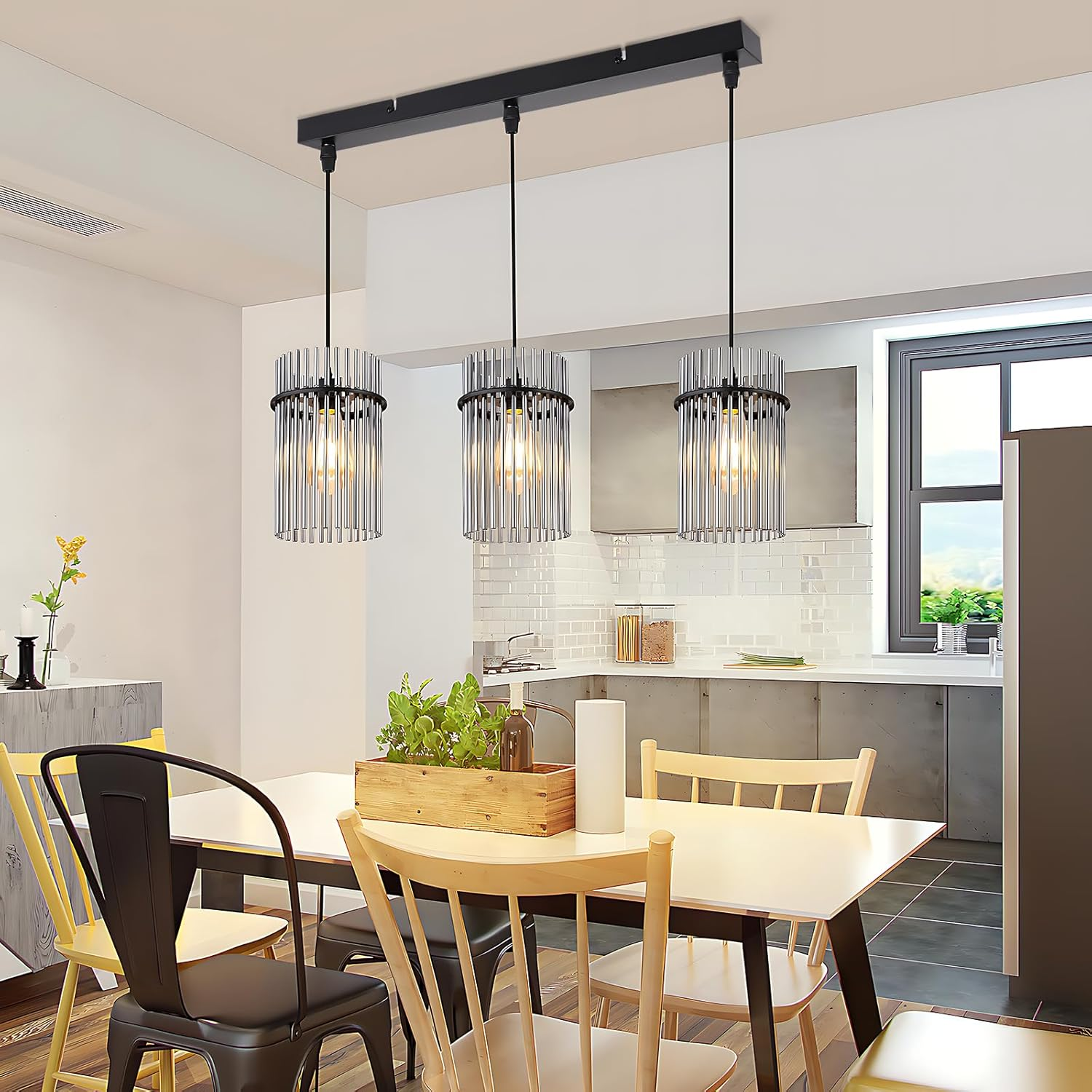 Sala da pranzo con lampadario, tavolo, sedie, piante e finestra. Lampade a sospensione sopra il tavolo.