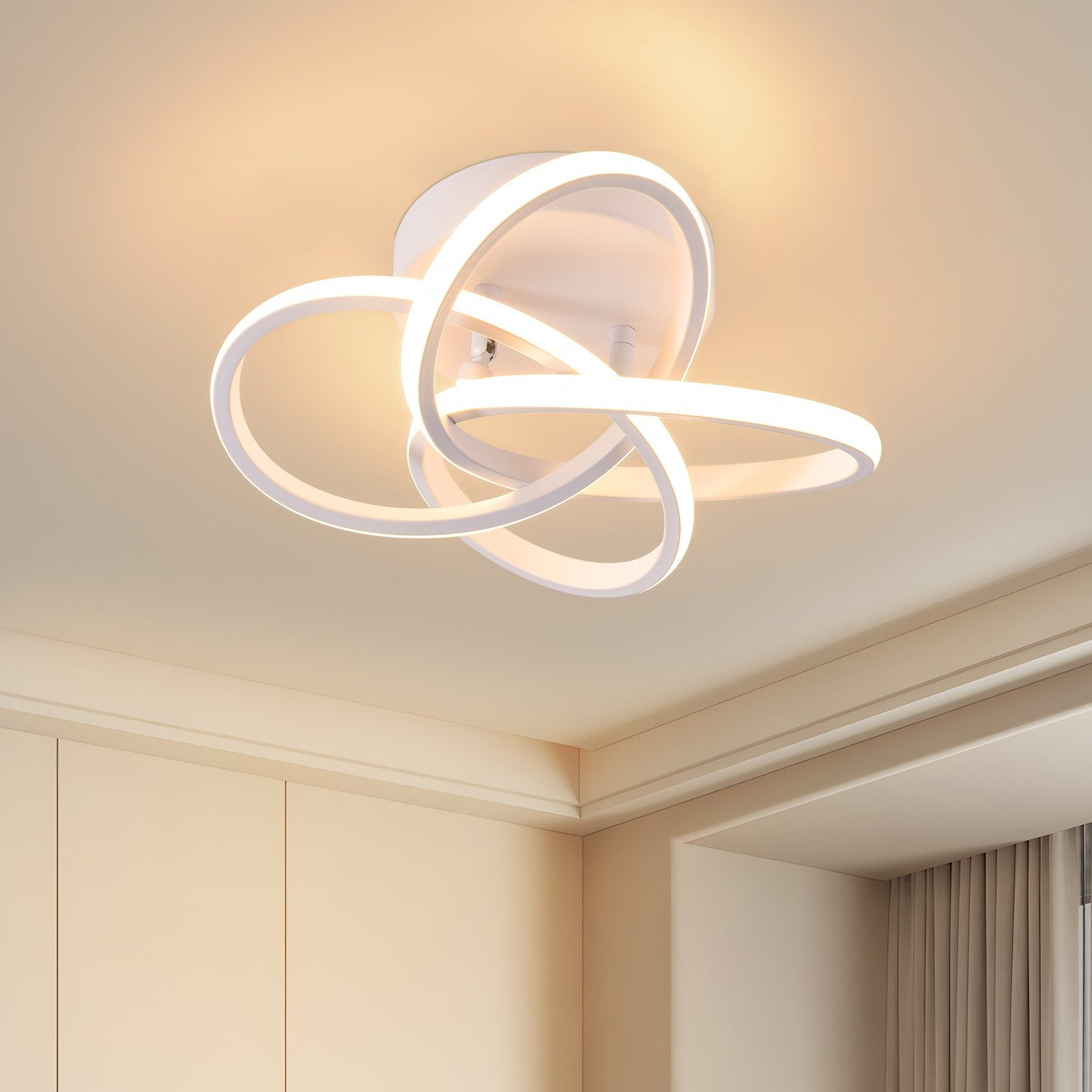 Una moderna plafoniera bianca con anelli interconnessi. Lo sfondo mostra soffitto e pareti color crema.