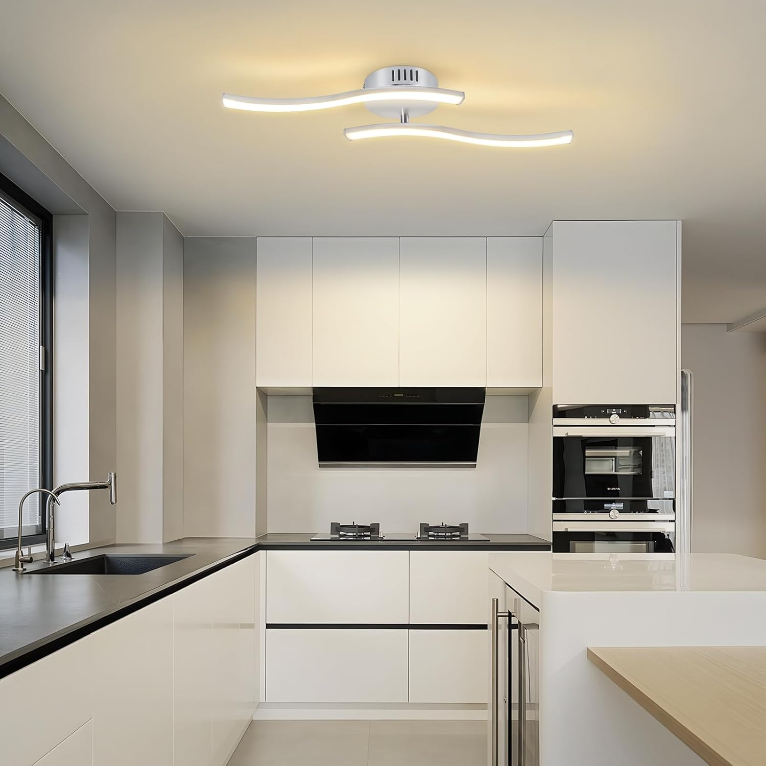 Cucina moderna con mobili bianchi, piani neri e una lampada da soffitto ondulata. Gli elettrodomestici includono una cappa e un forno.