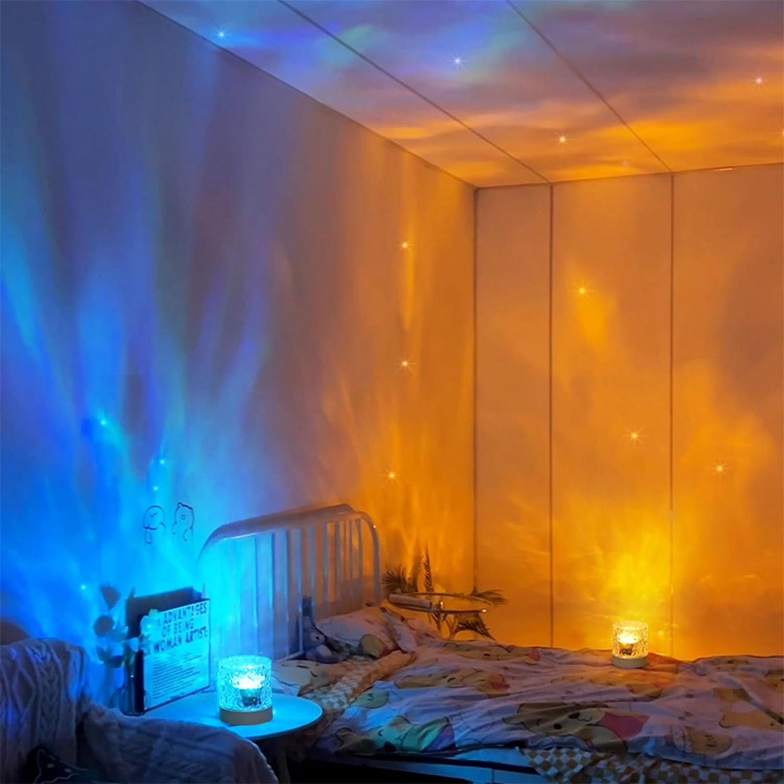 Ein Schlafzimmer mit blauen und orangenen Lichtprojektionen an den Wänden. Ein Bett und ein Tisch mit Lampe sind sichtbar.