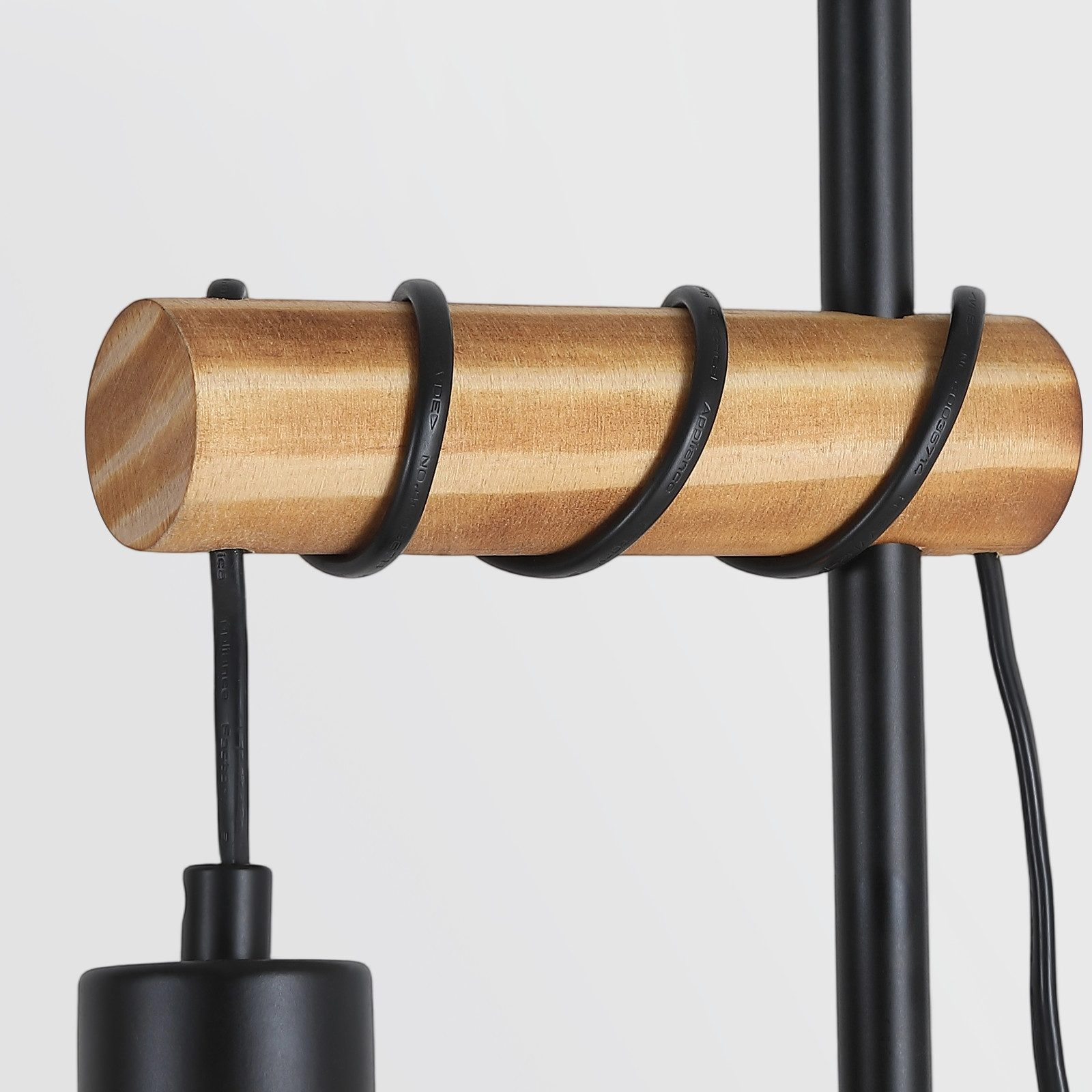 Primo piano di una lampada. Ha una barra di legno con fili neri e una base nera.