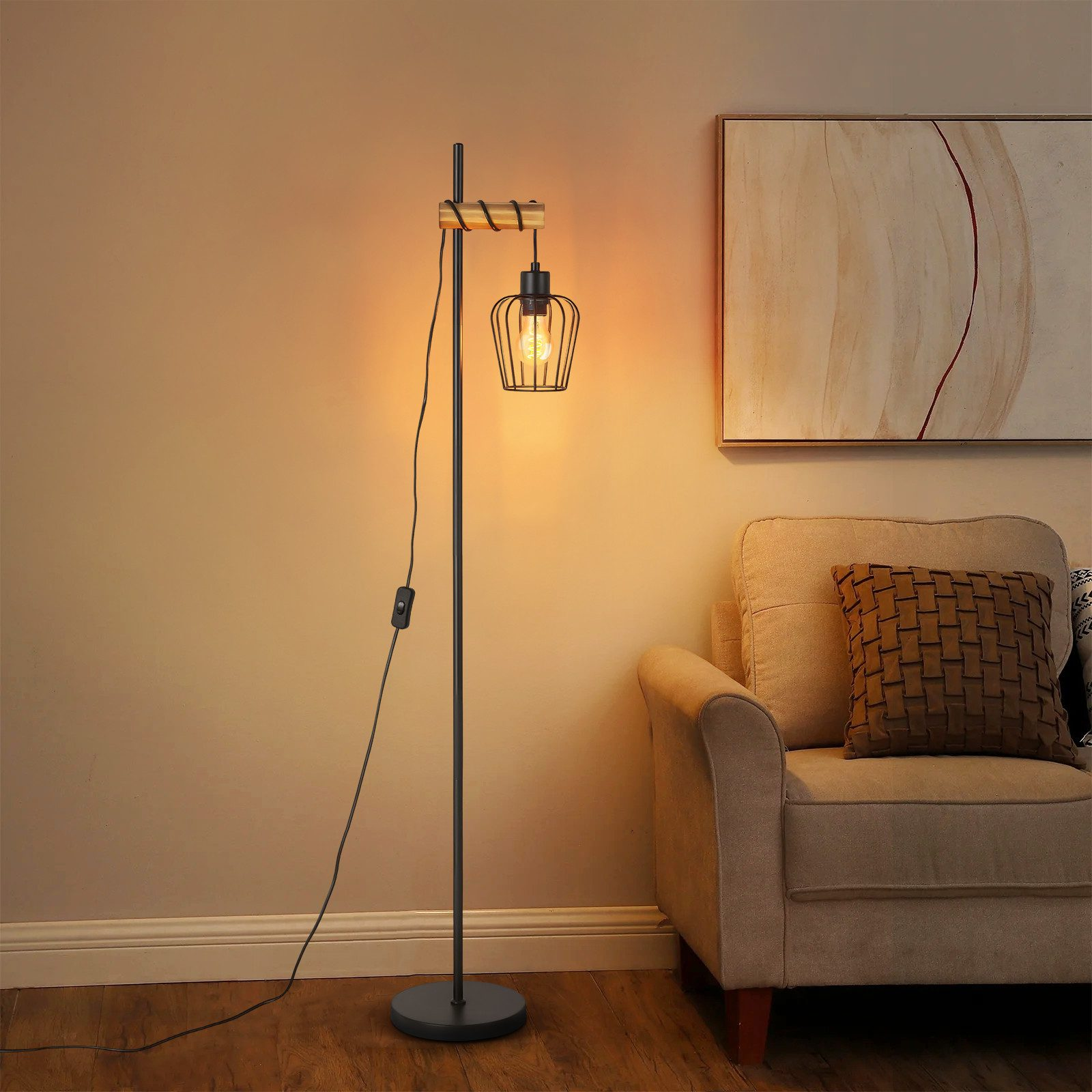 Una lampada da terra con un paralume a gabbia è illuminata. Un divano beige e un dipinto sono sullo sfondo.