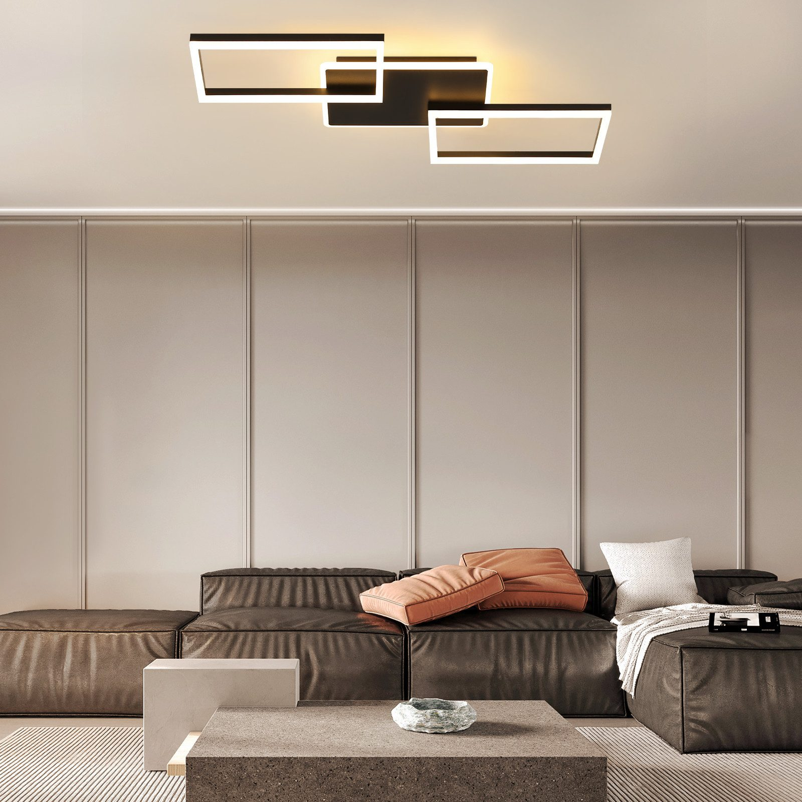 Soggiorno con lampada da soffitto moderna, divano in pelle scura, cuscini e tavolino.