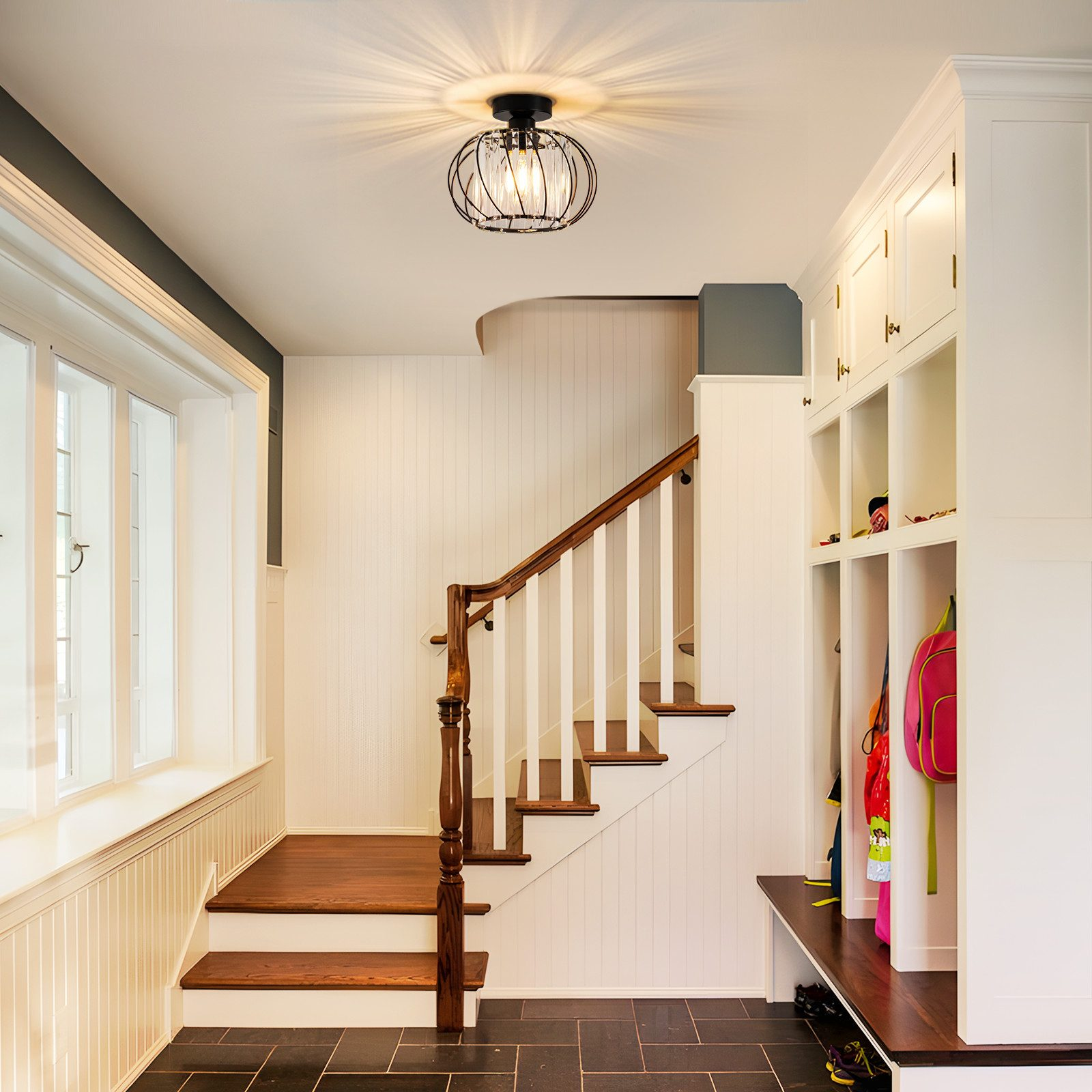 Scatto interno di un ingresso di casa con scale, un'unità di stoccaggio integrata e una combinazione di colori bianco e nero.