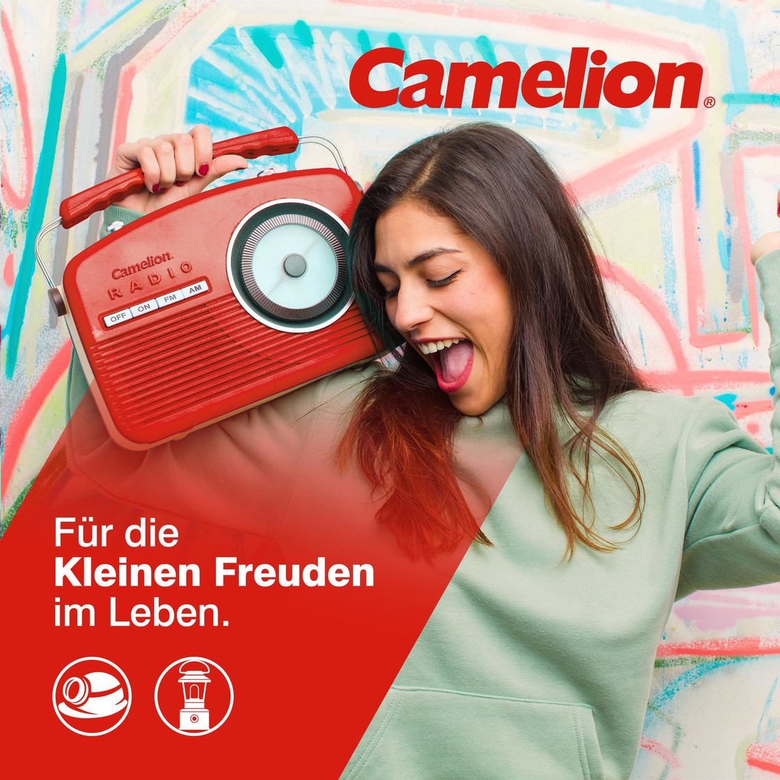 Een vrouw houdt een rode radio vast, breed glimlachend. De achtergrond is een graffiti-muur, en er staat tekst over de kleine geneugten van het leven.