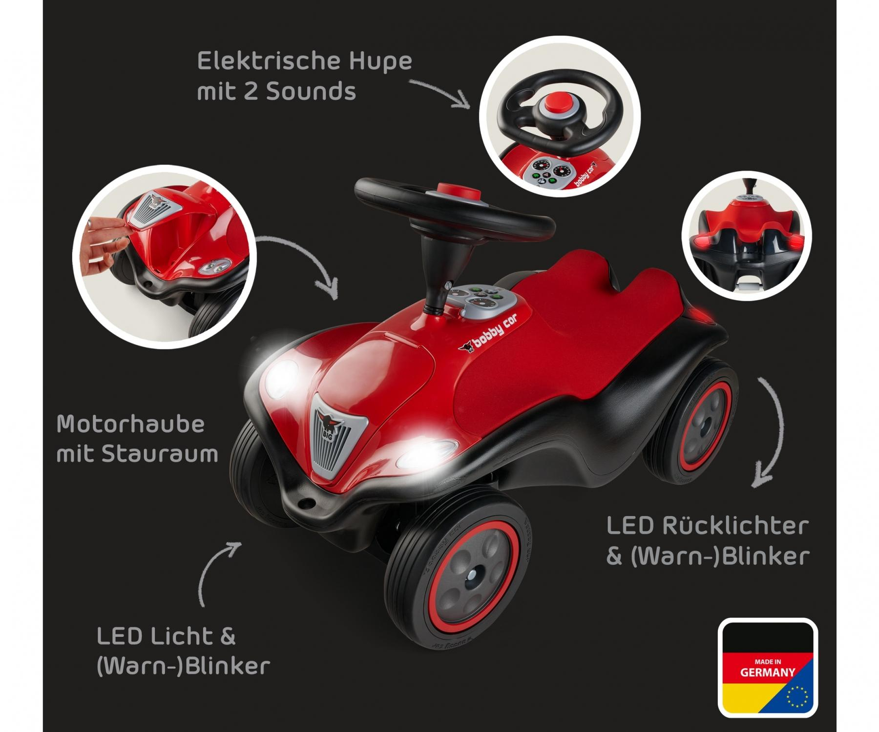 Rotes und schwarzes Spielzeugauto mit Lichtern und Lenkrad, mit deutschen Textbeschriftungen.