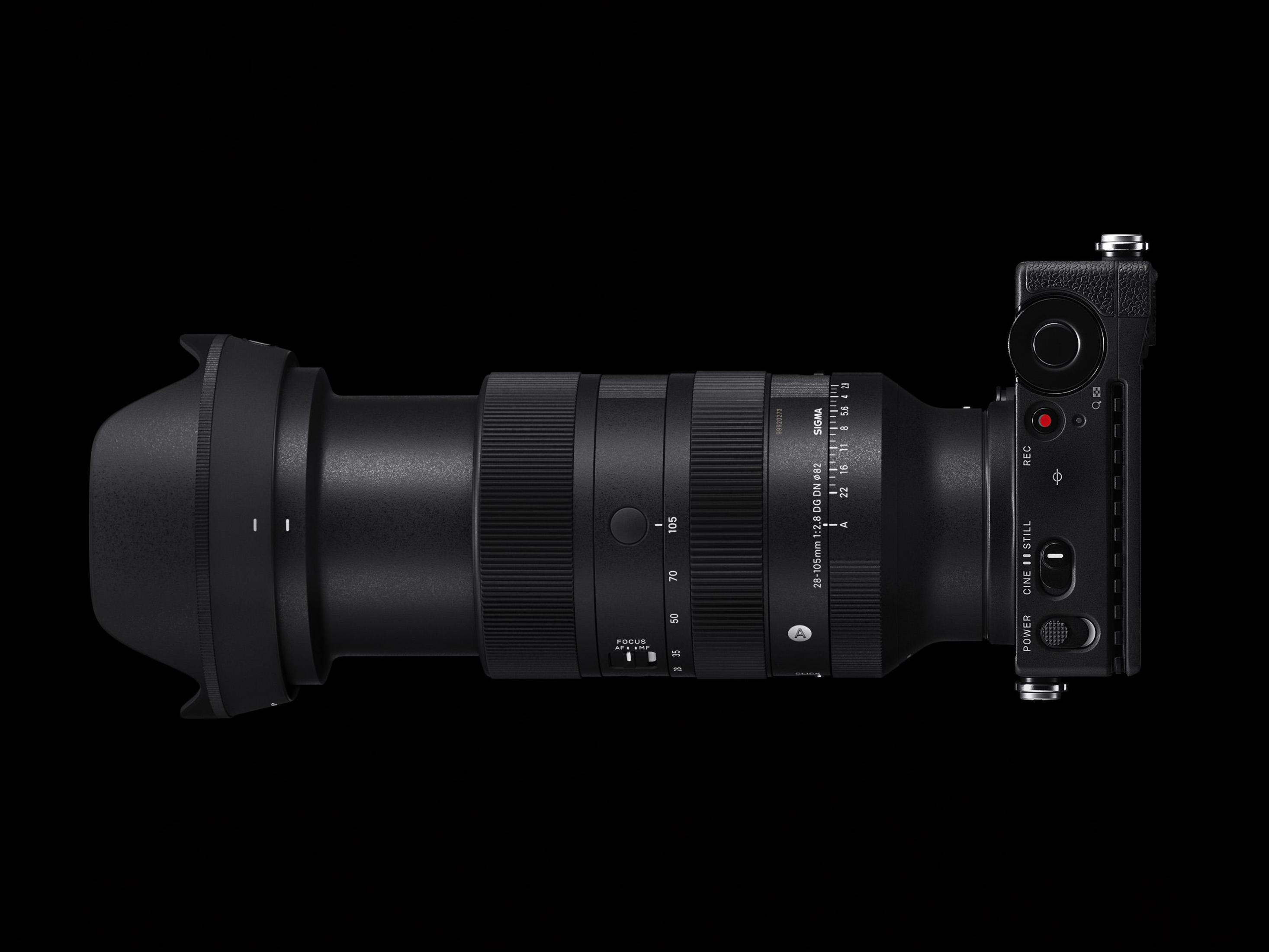 Czarny aparat Sigma z obiektywem. Obiektyw ma regulację ostrości i zoomu. Korpus aparatu ma przyciski i pokrętło.