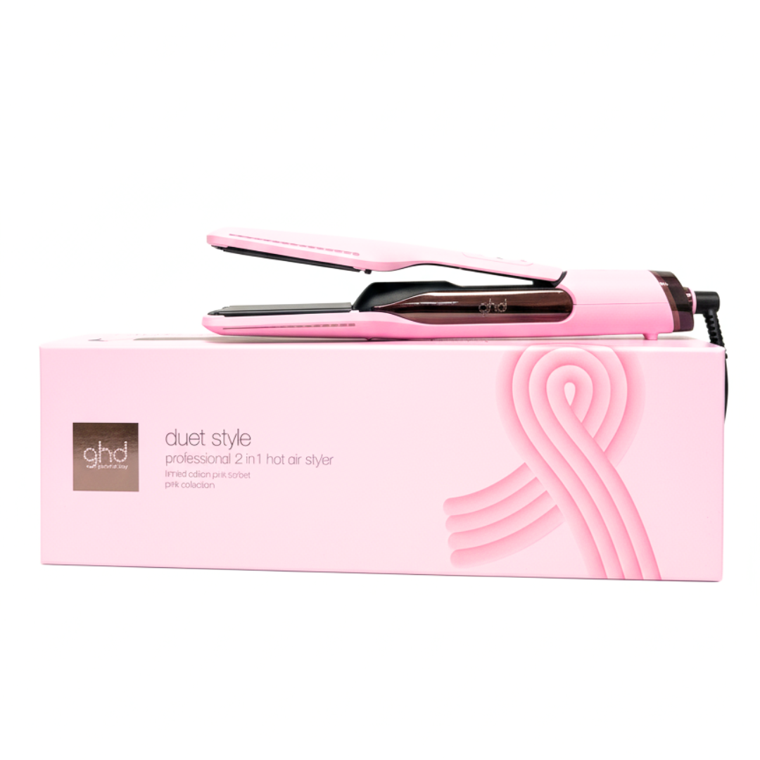 Ein pinkfarbener GHD Duet Style Haarstyler liegt auf einer pinkfarbenen Schachtel. Die Schachtel hat Text und ein Schleifendesign.