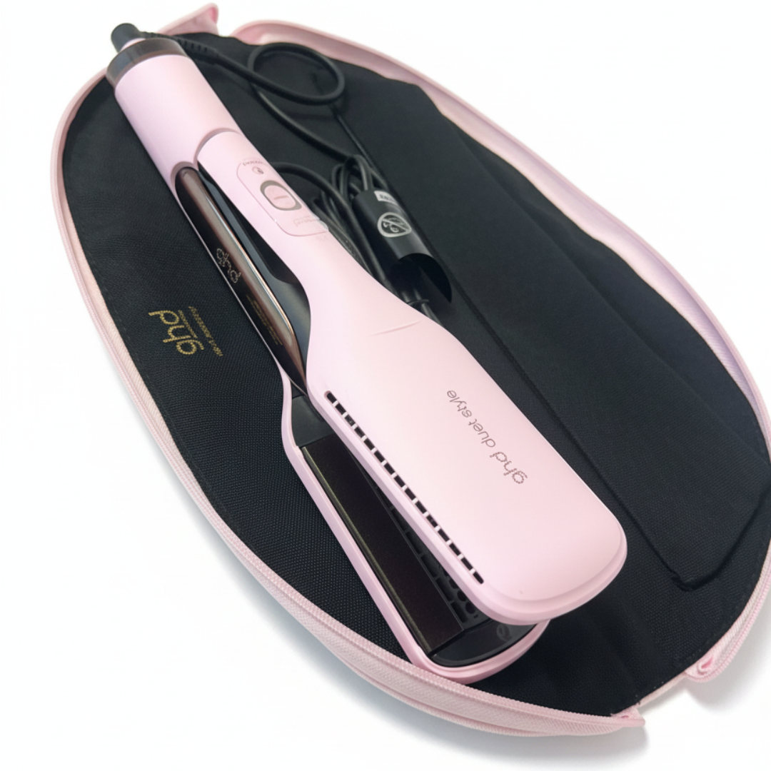 Ein pinkfarbener ghd Duet Style Haarglätter liegt offen in einem schwarzen Etui mit pinkfarbenem Reißverschluss. Ein Netzkabel ist vorhanden.