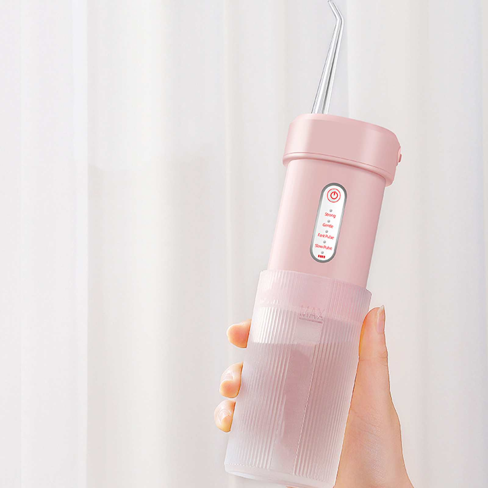 Ein rosa Munddusche wird gehalten. Es hat einen Wassertank und eine dünne Düse. Der Hintergrund ist ein weißer Vorhang.