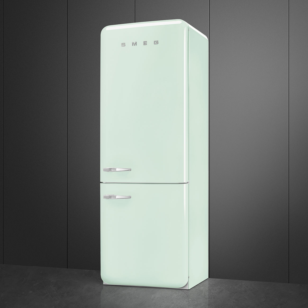 Un refrigerador Smeg verde menta se encuentra contra un fondo gris oscuro. Tiene dos puertas y manijas cromadas. La marca es visible.