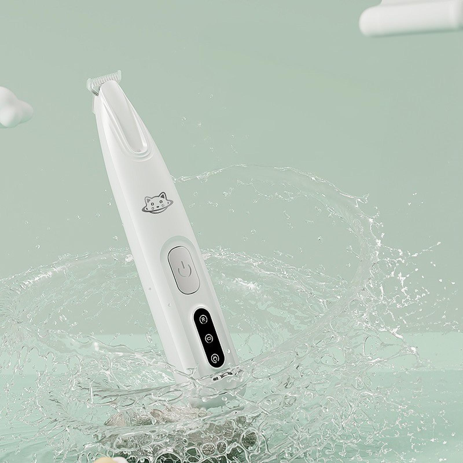 Ein weißer Haarschneider für Haustiere befindet sich im Wasser. Der Trimmer hat ein Katzenlogo und Knöpfe. Wasser spritzt herum.