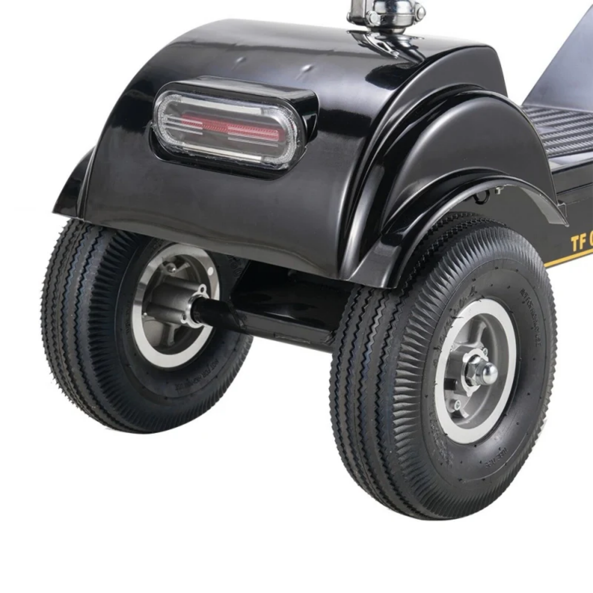 Zbliżenie tylnej części czarnego skutera inwalidzkiego. Widoczne są dwie opony, błotnik i światło tylne.