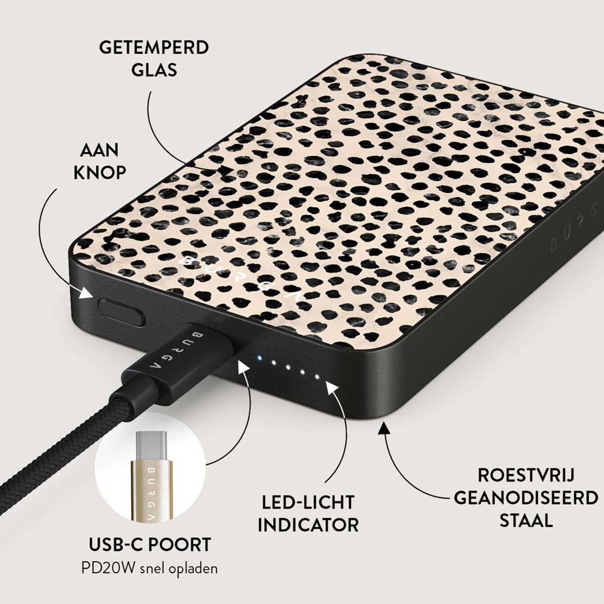 Une batterie externe noire et beige avec un motif à pois. Un câble USB-C est connecté. Des étiquettes indiquent des fonctionnalités comme le bouton et l'acier.