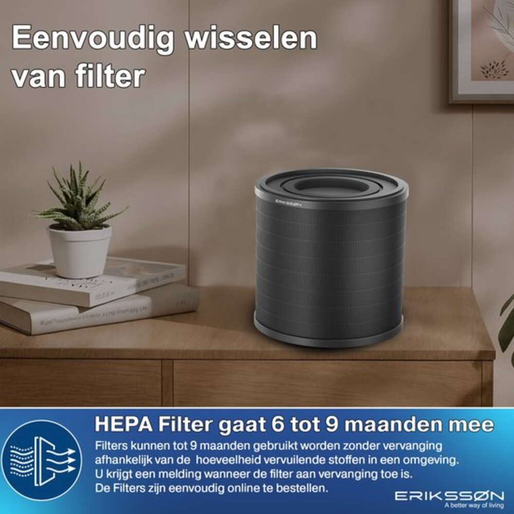 A dark air purifier sits on a wooden surface. A small plant in a white pot rests on books to the left.
