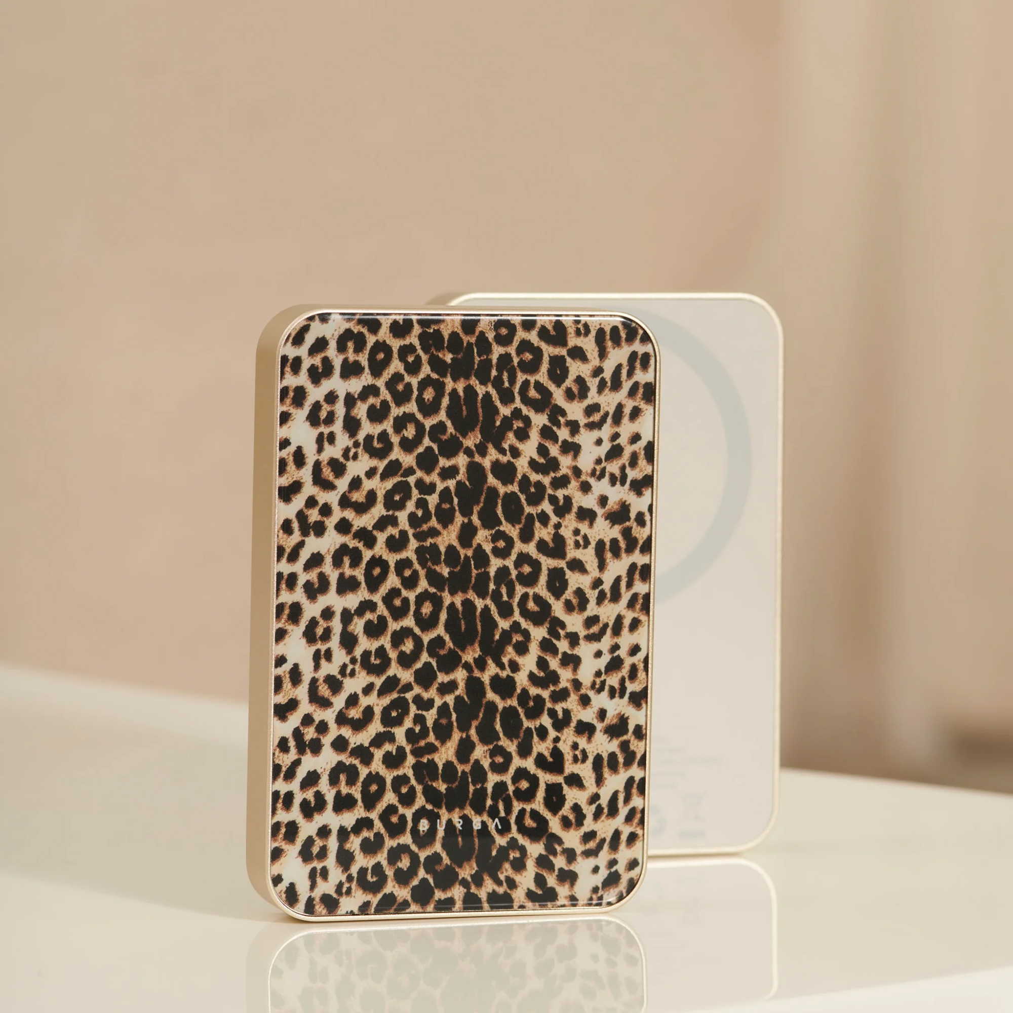 Deux chargeurs sans fil rectangulaires. Le devant a un motif léopard, l'arrière est blanc. Les deux sont sur une surface blanche.