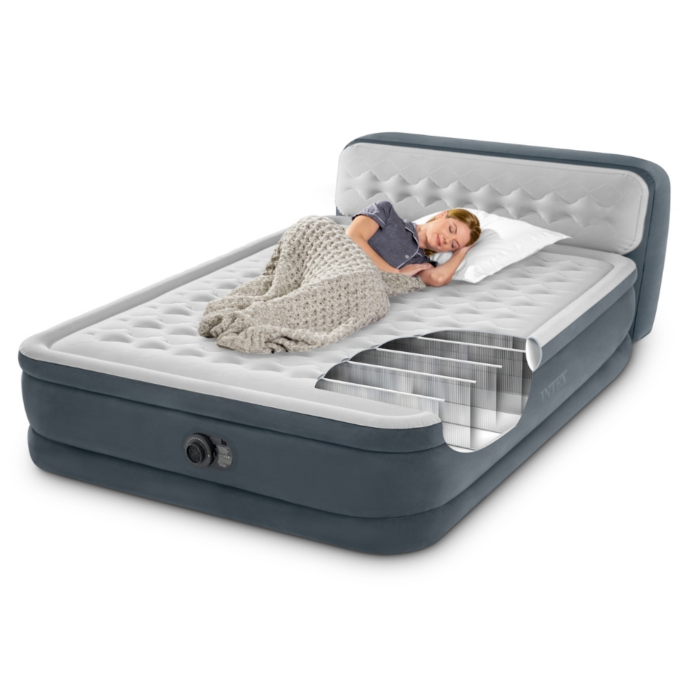 Kobieta śpi na dmuchanym łóżku. Część łóżka jest odcięta, pokazując wewnętrzną strukturę. Przykrywa ją koc.