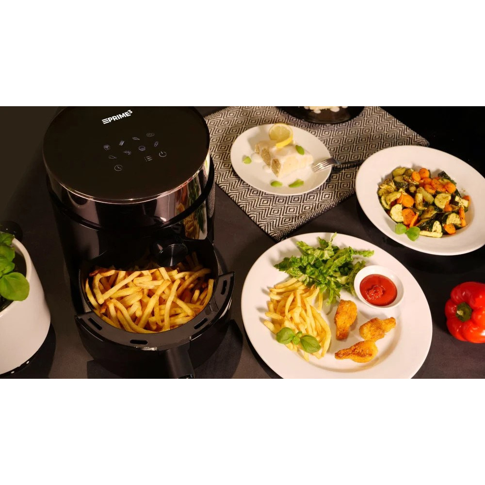 Una friggitrice ad aria con patatine fritte, piatti di cibo, tra cui pollo fritto, verdure e torta. Un peperone rosso è a destra.