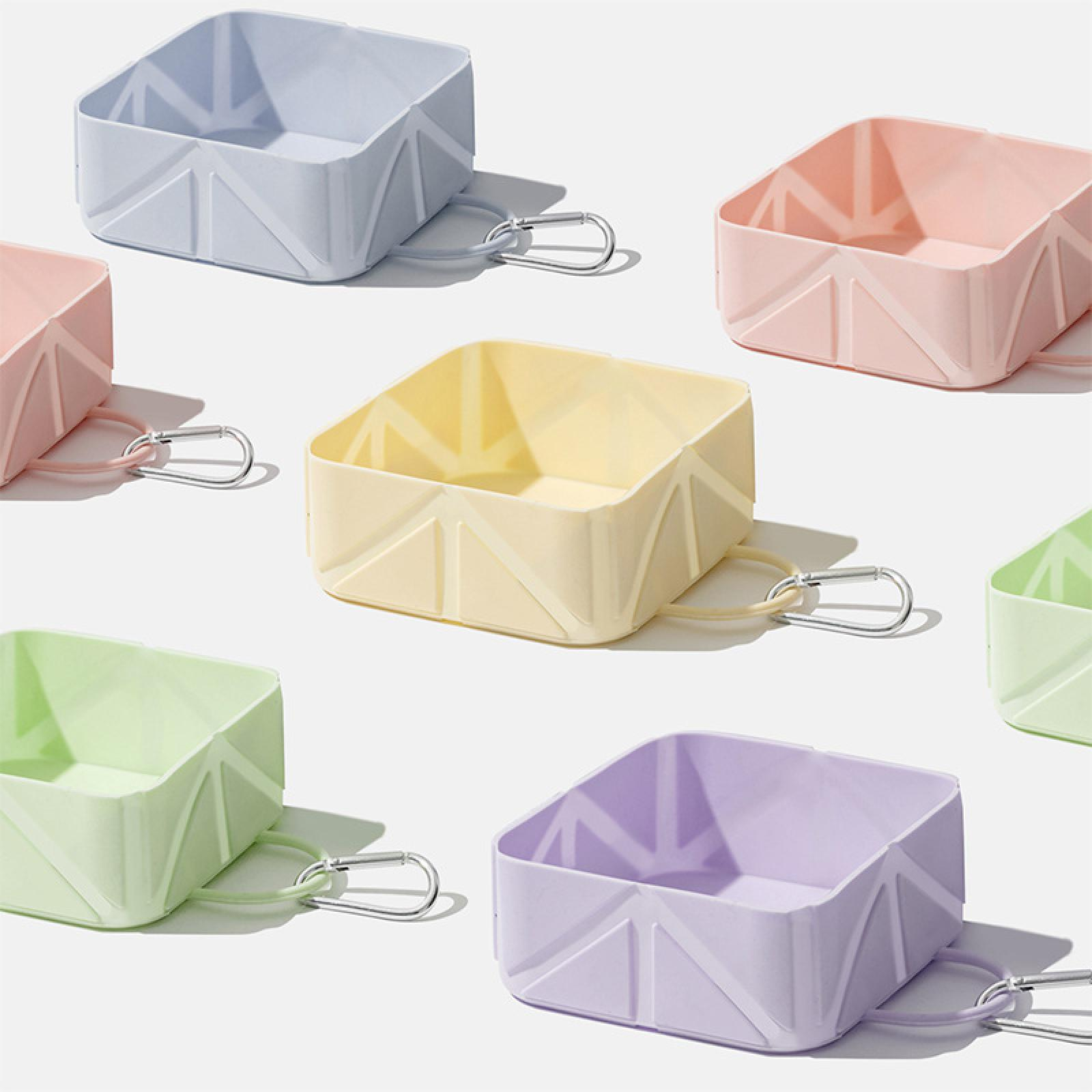 Bunte, quadratische, faltbare Behälter mit Karabinerhaken. Farben: Blau, Rosa, Gelb, Grün und Lila, angeordnet auf weißem Hintergrund.