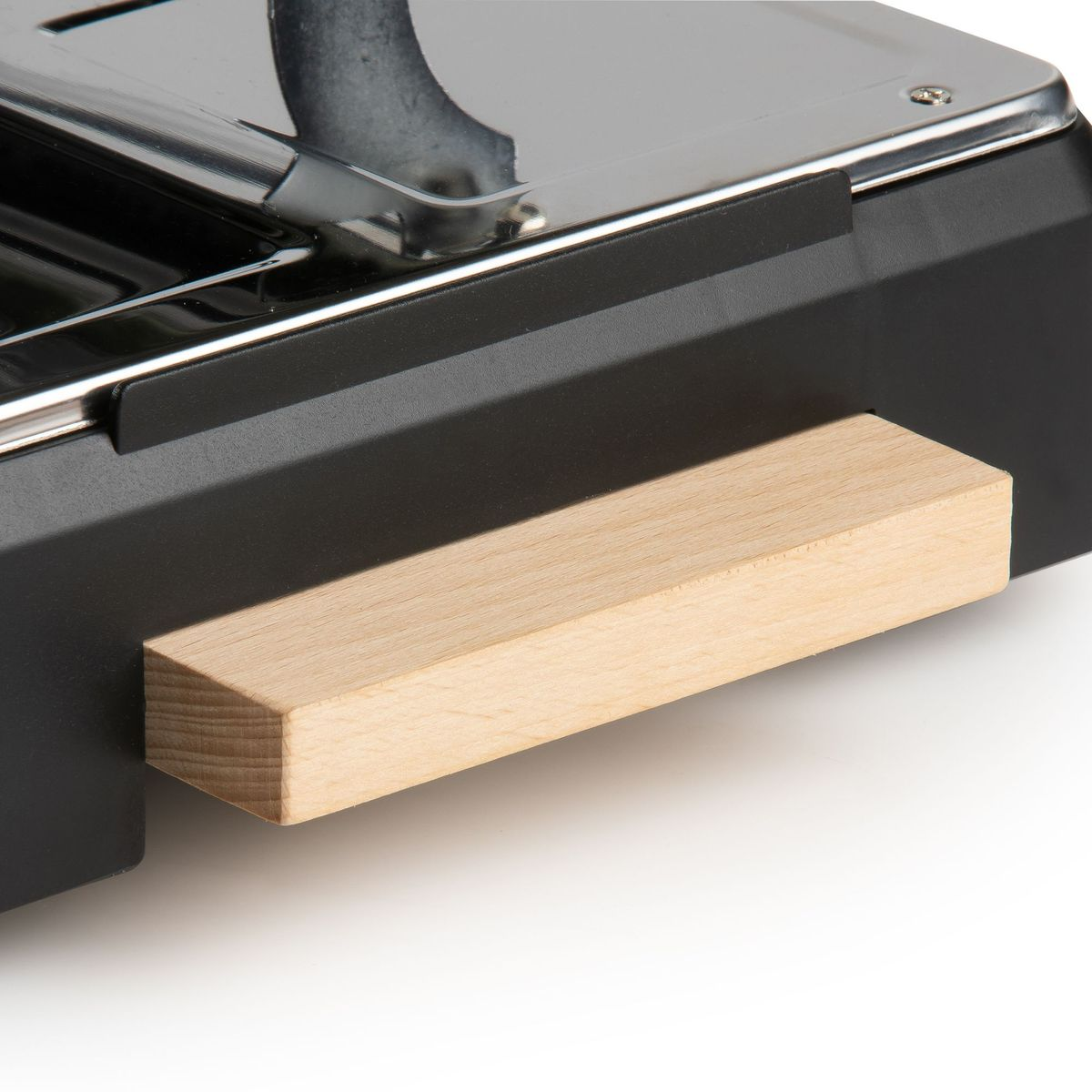 Nahaufnahme eines schwarzen Objekts mit Holzgriff. Die Oberseite ist metallisch. Der Griff ist ein hellbrauner rechteckiger Block.