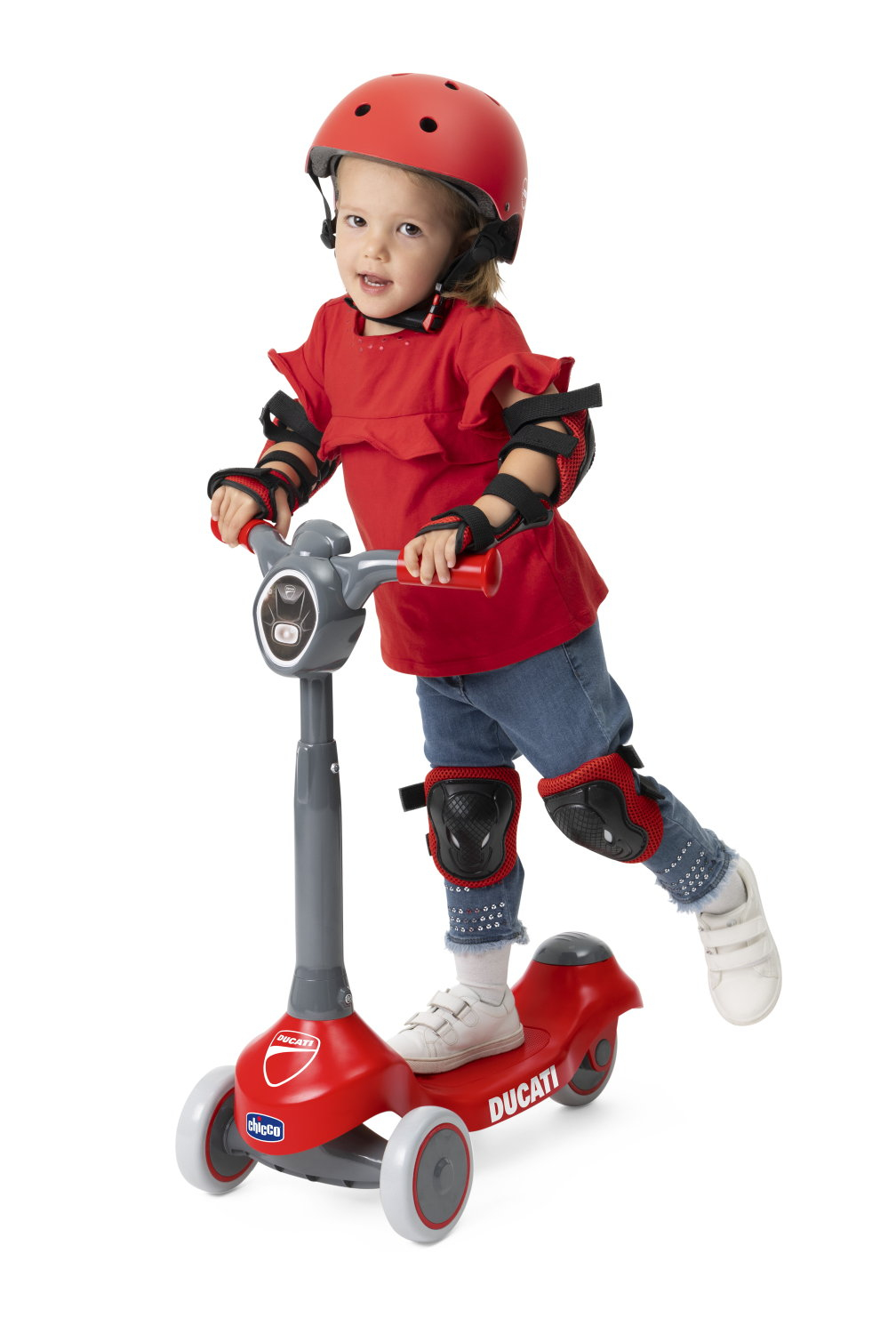 Ein junges Kind mit rotem Helm und Schutzkleidung fährt einen roten Ducati-Roller. Das Kind lächelt und steht auf weißem Hintergrund.