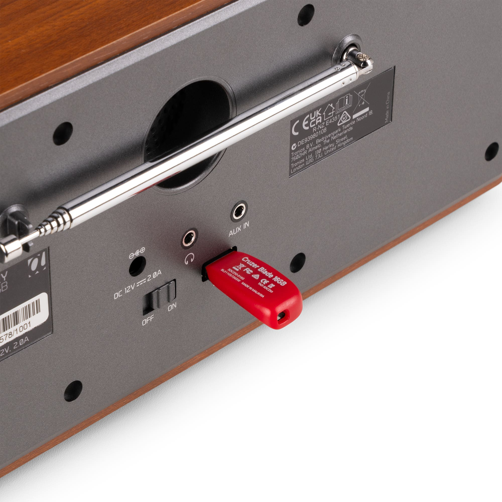 Primer plano de la parte trasera de una radio. Hay un USB rojo enchufado. Se ve una antena plateada y detalles.