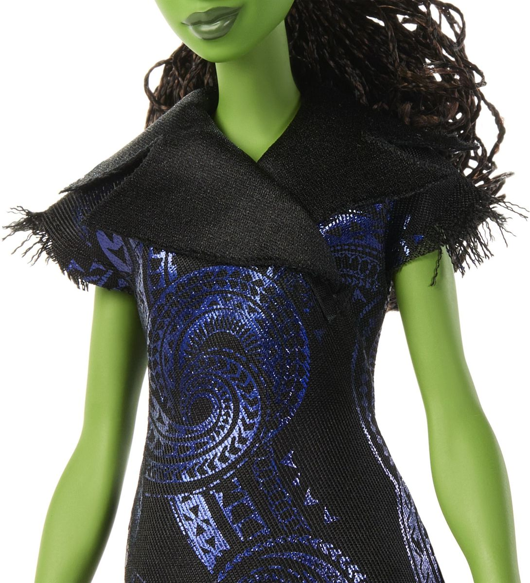 Una muñeca de piel verde con un vestido negro con patrones azules y un cuello negro. La muñeca tiene cabello castaño y una leve sonrisa.