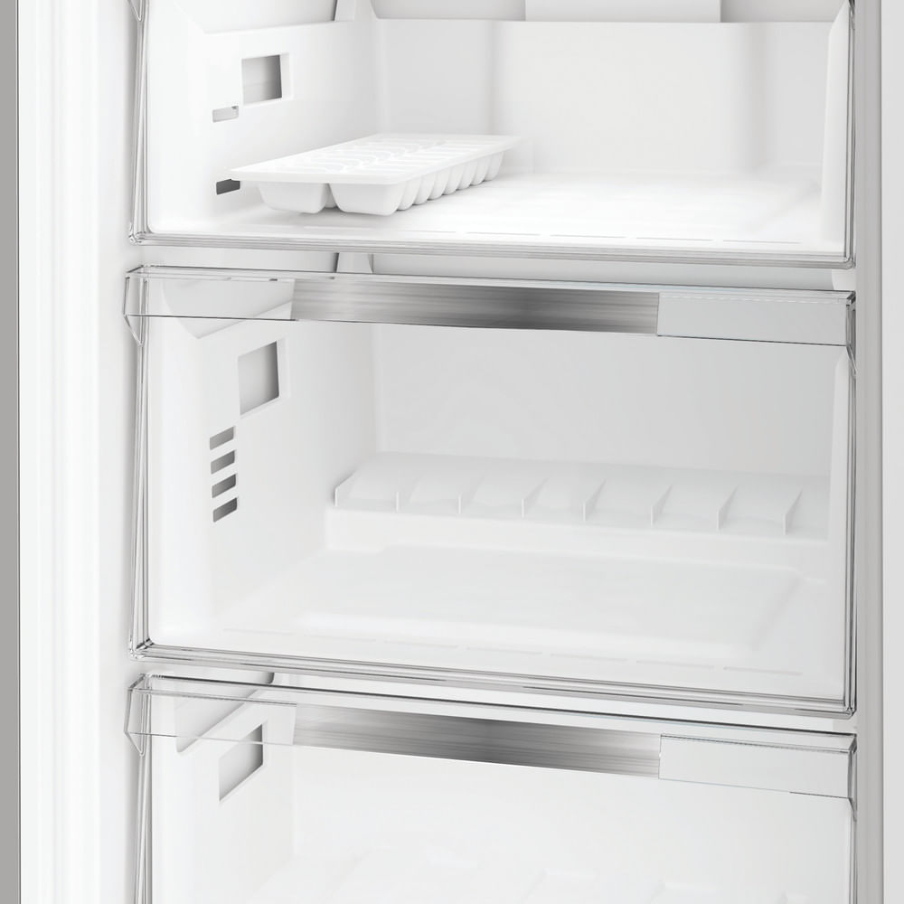 Interno di frigorifero bianco vuoto. Visibili ripiani, cassetti e un vassoio per cubetti di ghiaccio. Tutte le superfici sono pulite e bianche.