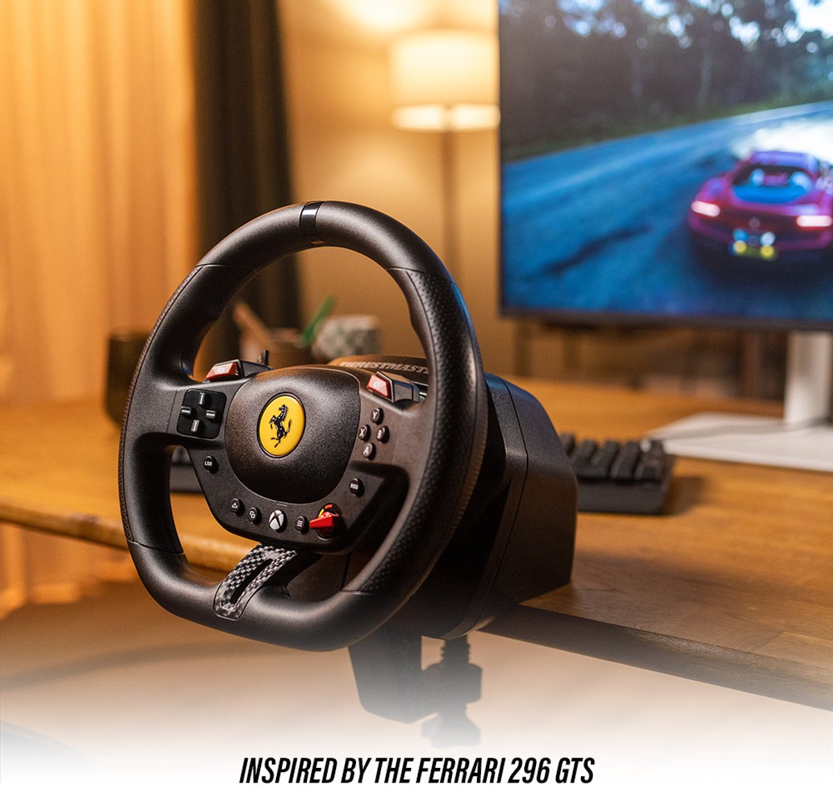 Un volante de carreras con el logo de Ferrari está sobre un escritorio. Una pantalla muestra un coche de carreras. El escritorio es color madera.