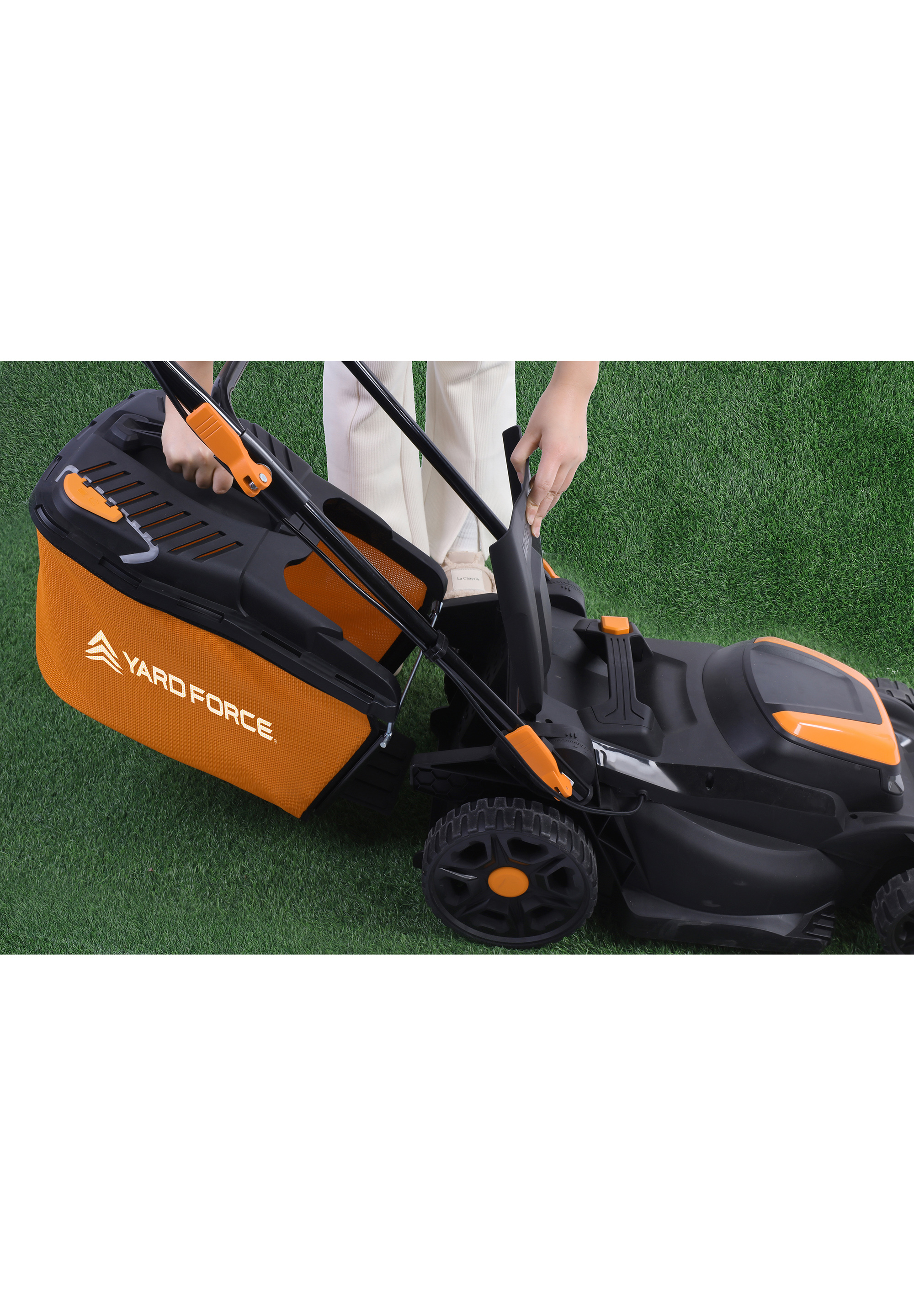 Eine Person befestigt einen orangefarbenen Beutel an einem schwarzen Rasenmäher auf einem grünen Rasen. Yard Force-Logo sichtbar.