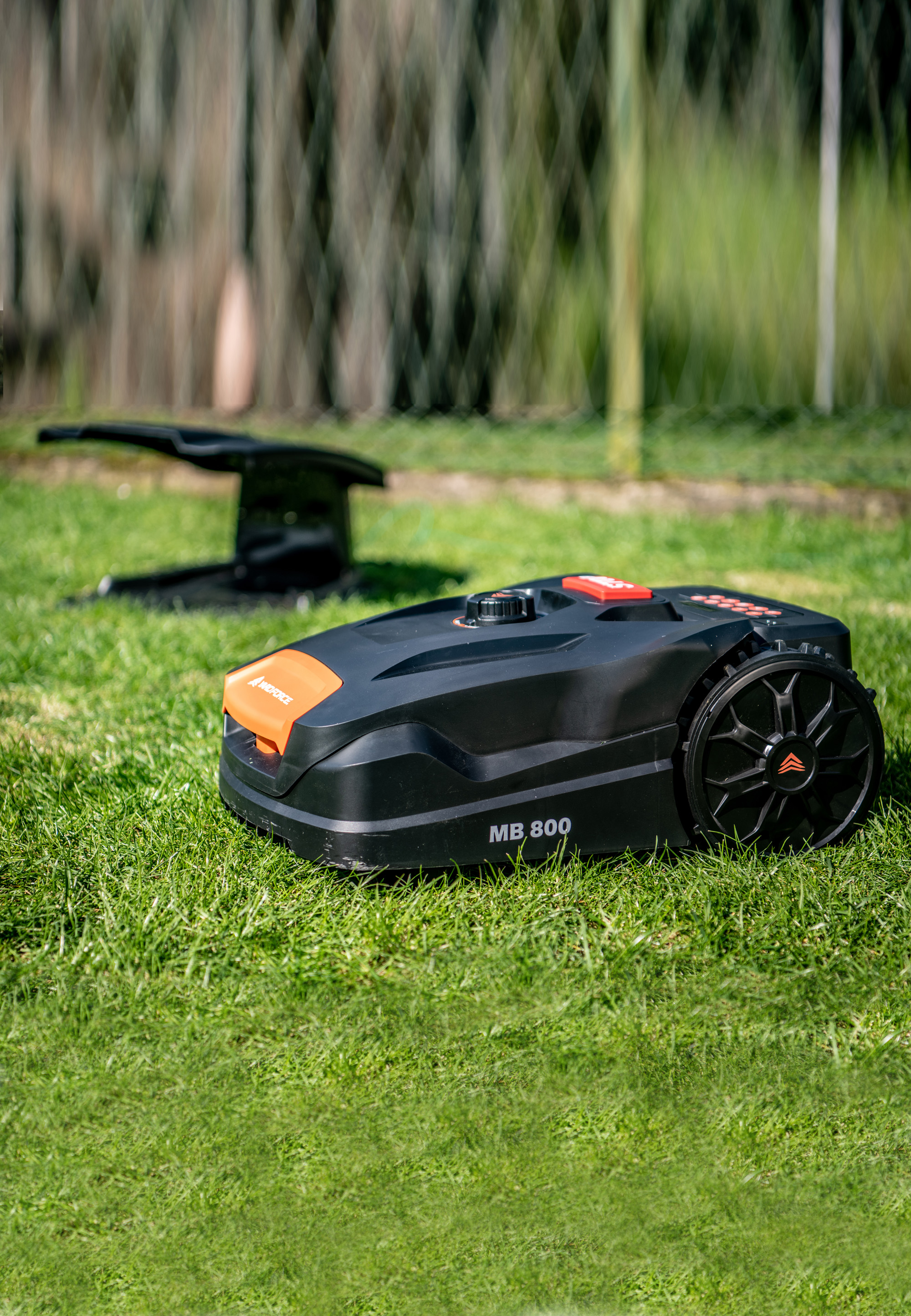 Ein schwarzer Roboter-Rasenmäher auf grünem Gras. Ein orangefarbenes Logo befindet sich auf der Vorderseite.
