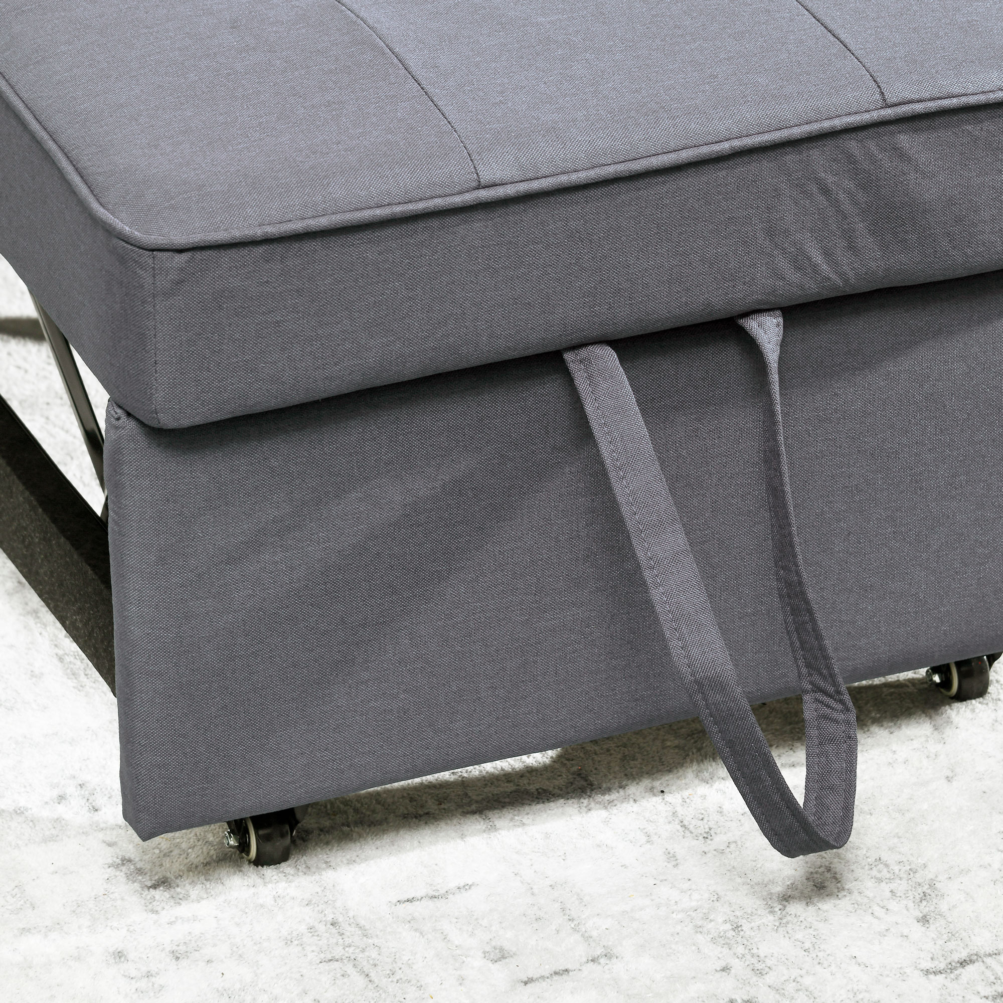 Primo piano di un divano letto grigio estraibile. Il tessuto è grigio e ci sono maniglie.
