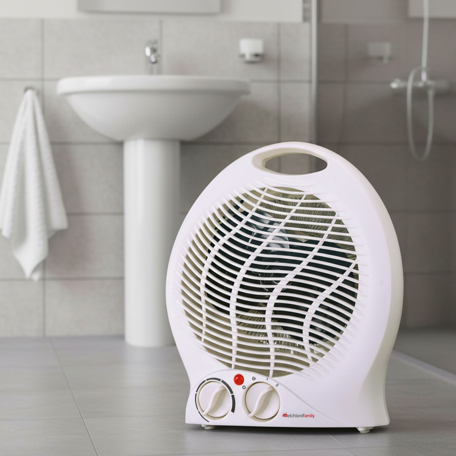 Biały grzejnik elektryczny w łazience. W tle widoczna umywalka i ręcznik. Podłoga i ściany są wyłożone kafelkami.