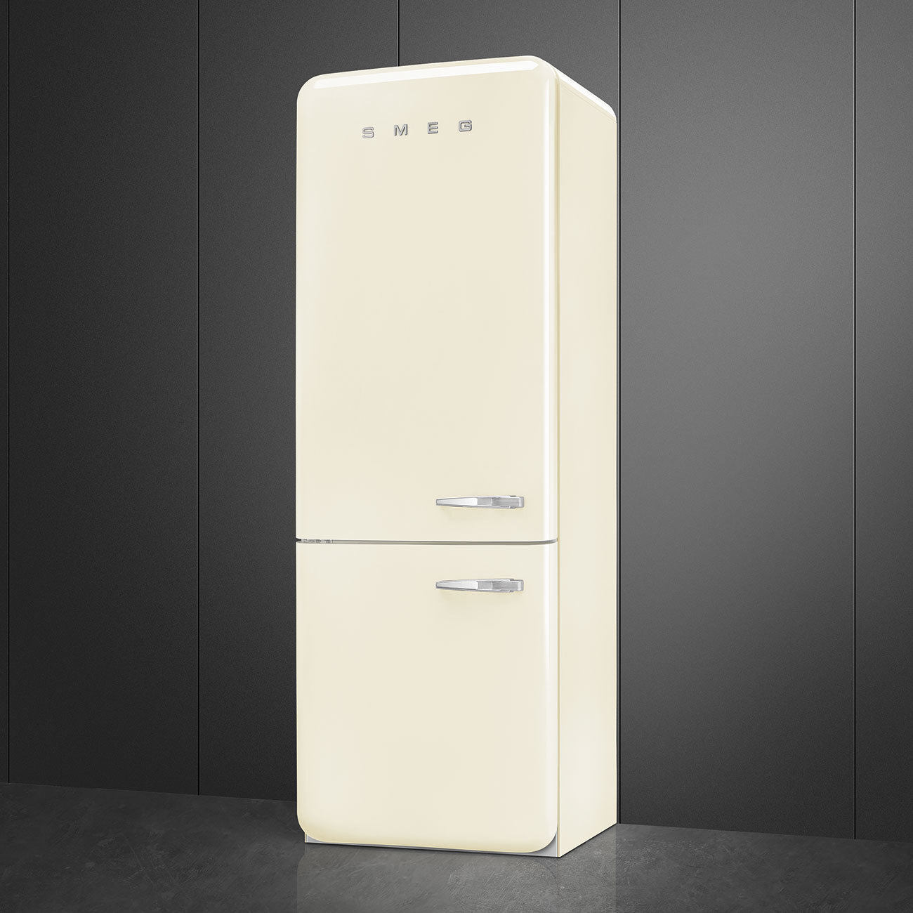 Un refrigerador Smeg color crema se encuentra contra una pared de paneles gris oscuro. Mangos cromados y el logo Smeg visibles.