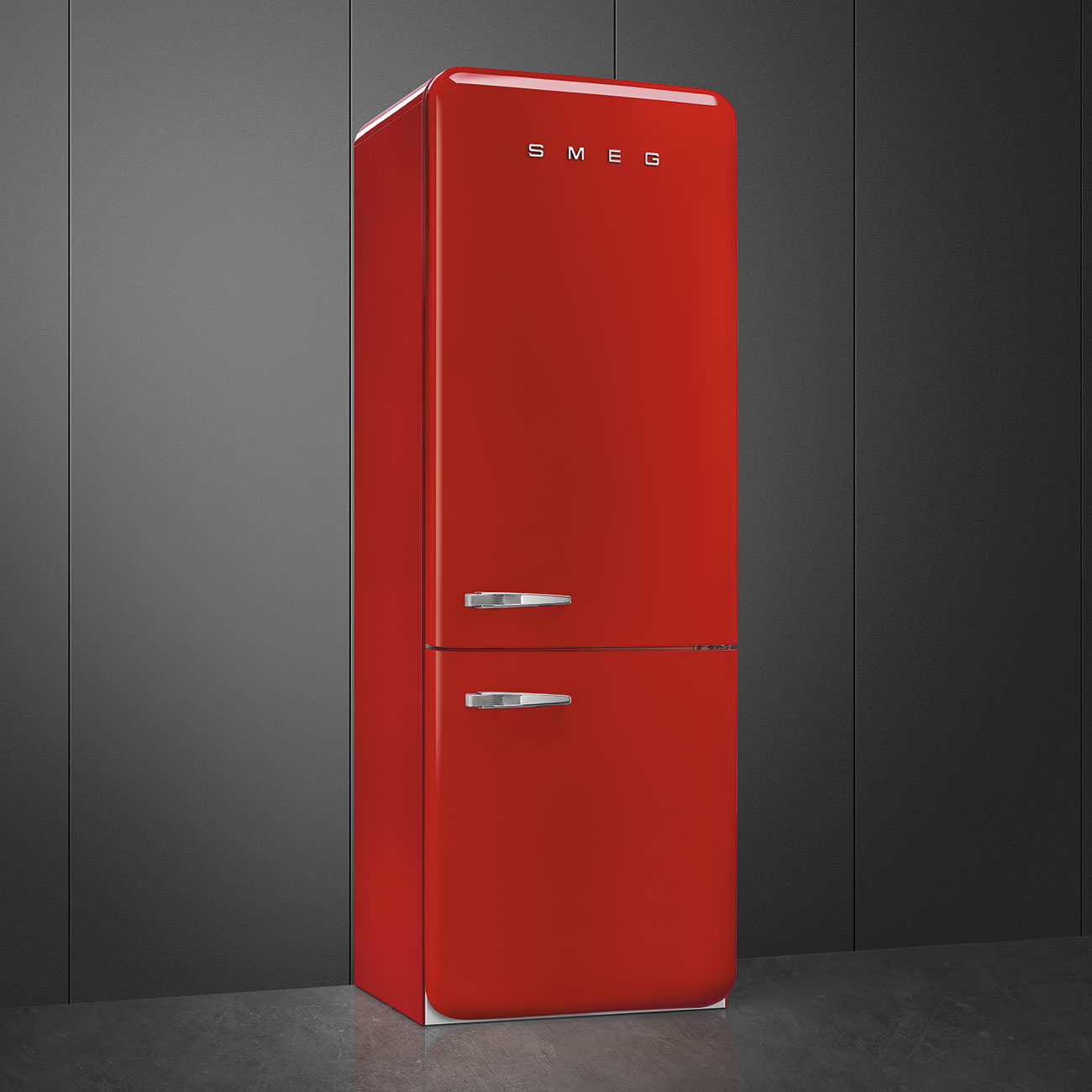 Un refrigerador SMEG rojo se encuentra contra una pared gris. El refrigerador tiene dos manijas y un diseño retro. El fondo es oscuro.