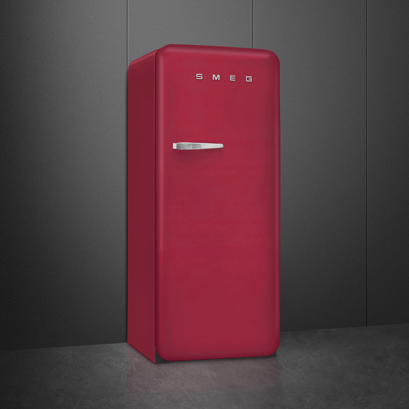 Un frigorifero SMEG rosso è contro un muro grigio scuro strutturato. Ha una maniglia argentata e il logo SMEG in alto.