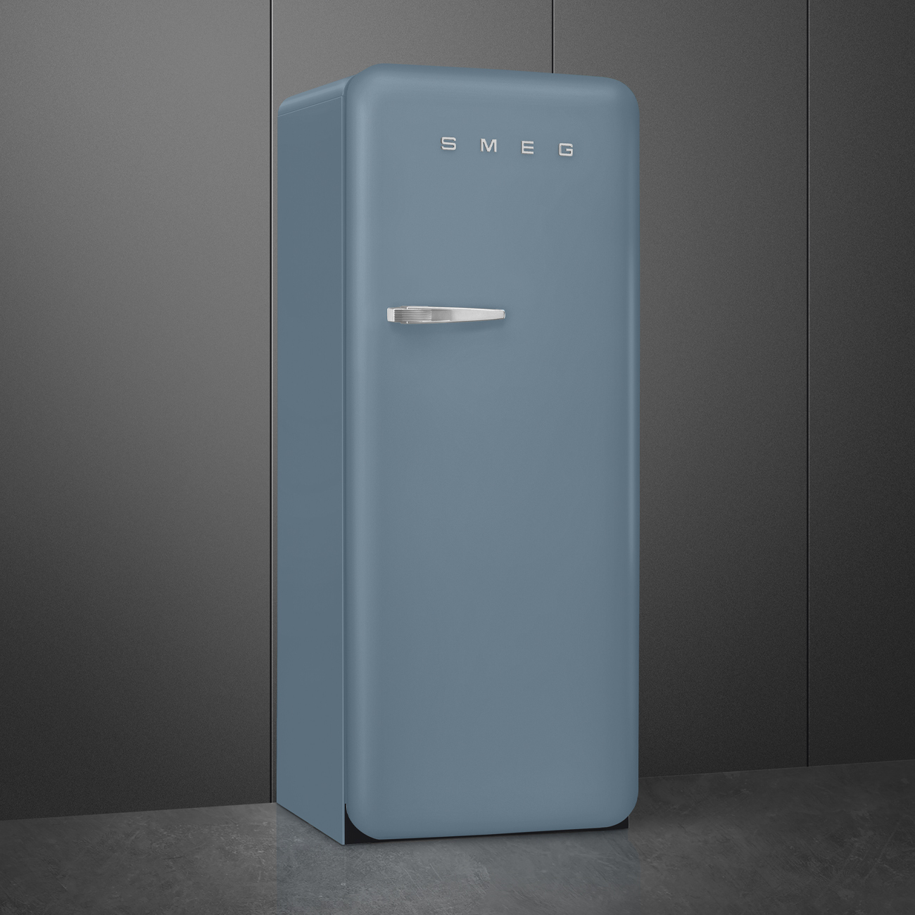 Ein blauer SMEG-Kühlschrank steht vor einer dunkelgrauen Wand. Er hat einen silbernen Griff und das SMEG-Logo oben.